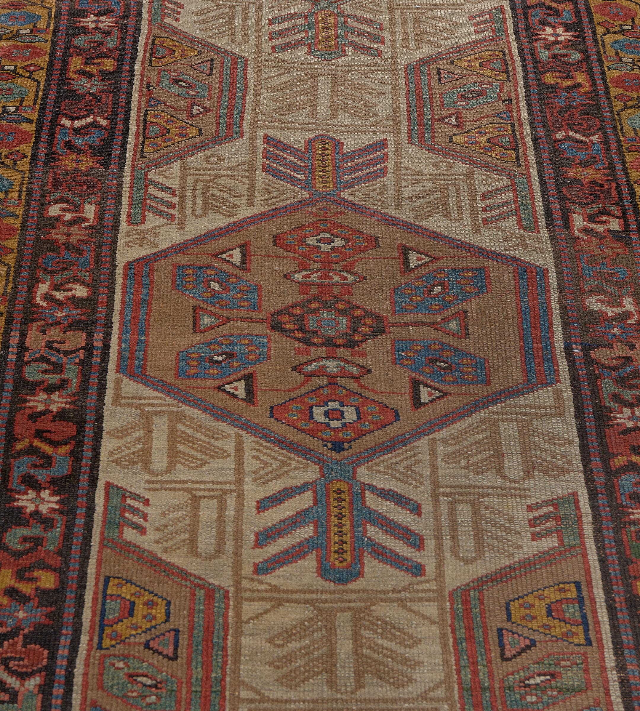 This antique Persian Serab runner has a light buff-brown field with angular floral motifs around a column of four camel-brown hexagonal lozenges with serrated palmettes each containing a central polychrome lozenge medallion with four light blue