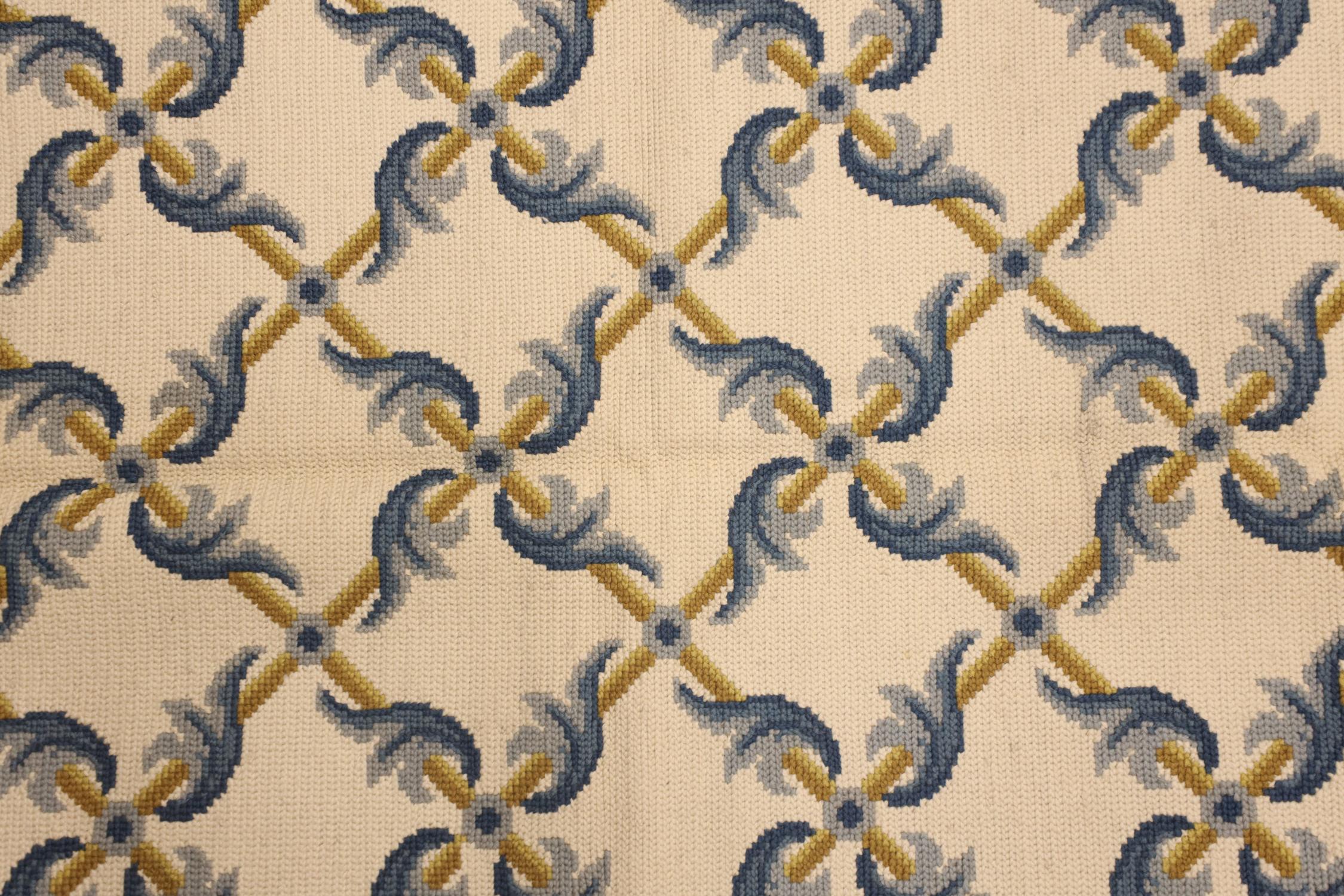 This elegant wool needlepoint is a classic example of a modern Portuguese style rug woven by hand in China in the early 21st century. The design in this piece has been delicately woven with a symmetrical pattern made up of blue and mustard accents