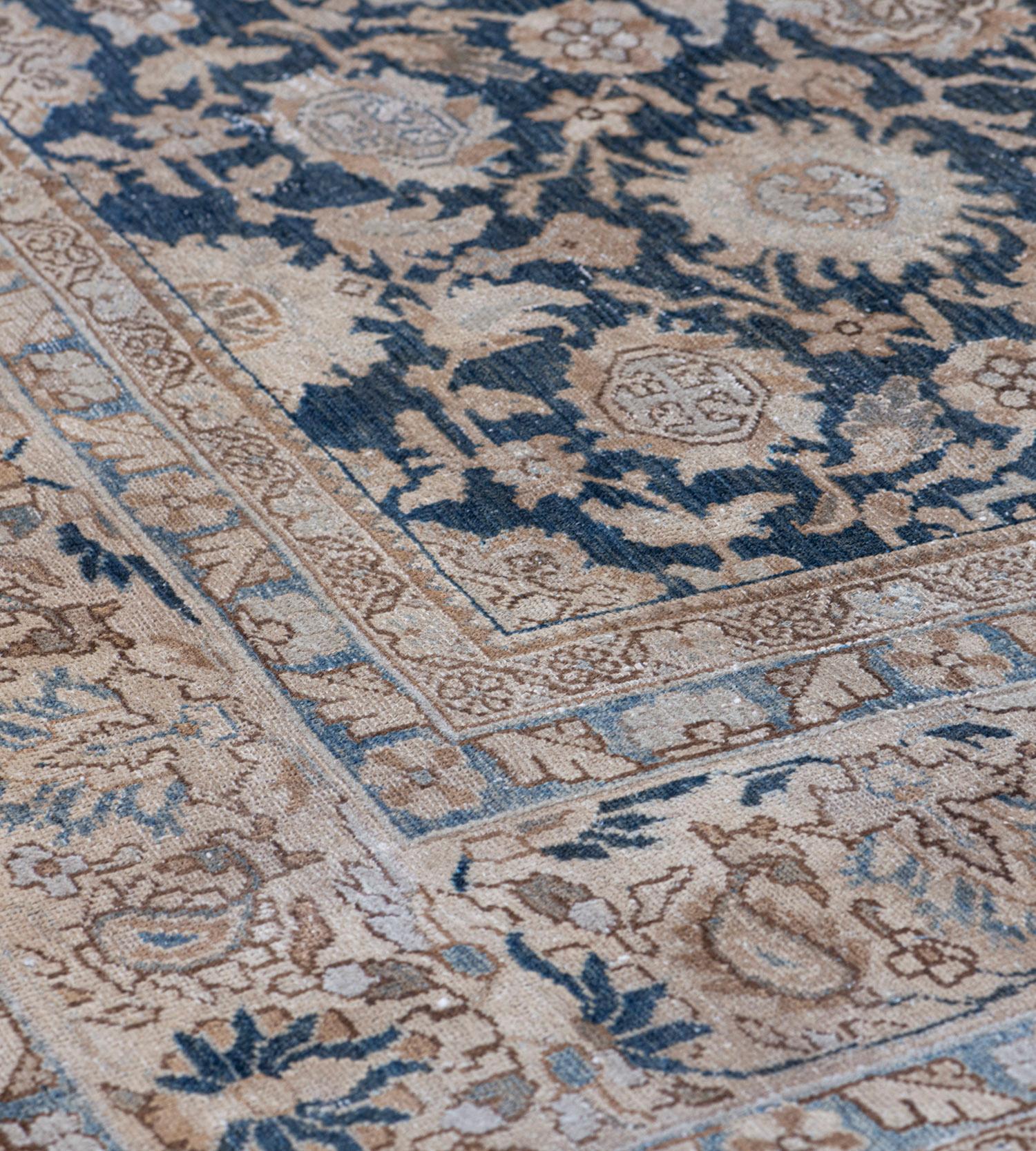 This traditional handwoven Persian Malayer rug has an indigo overall field of palmette pendants issuing a dense network of flowering vines, in an imperial beige scrolling palmette border, between complementary floral vine stripes.