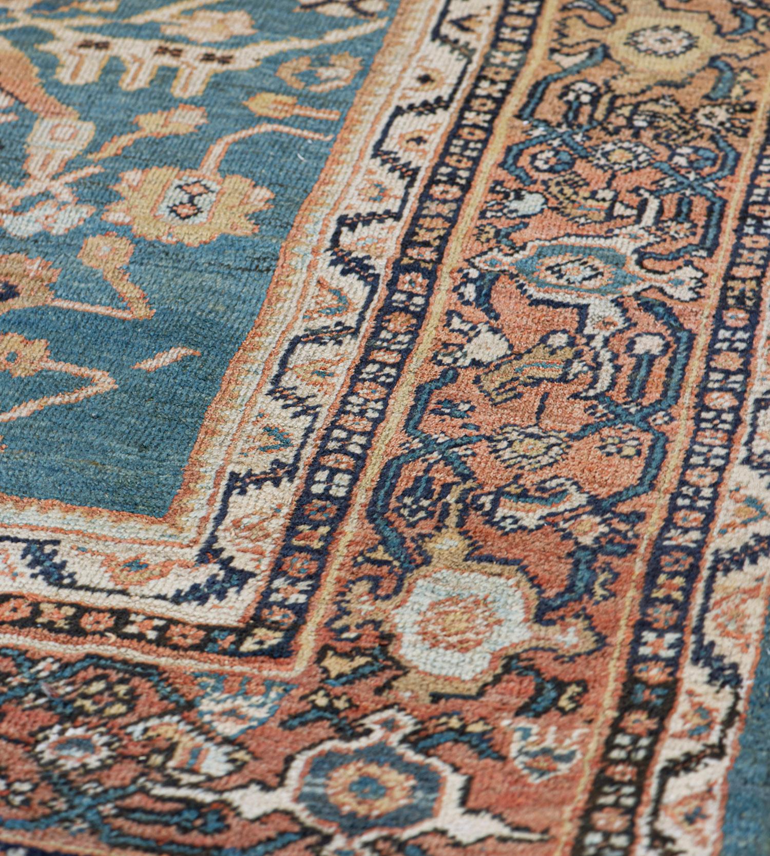This traditional handwoven Persian Sultanabad rug has a shaded medium blue field of regal palmette pendants issuing lozenge vine forming lattice, in a shaded brick-red-orange interlocked turtle palmette border, between nuanced vine and floral