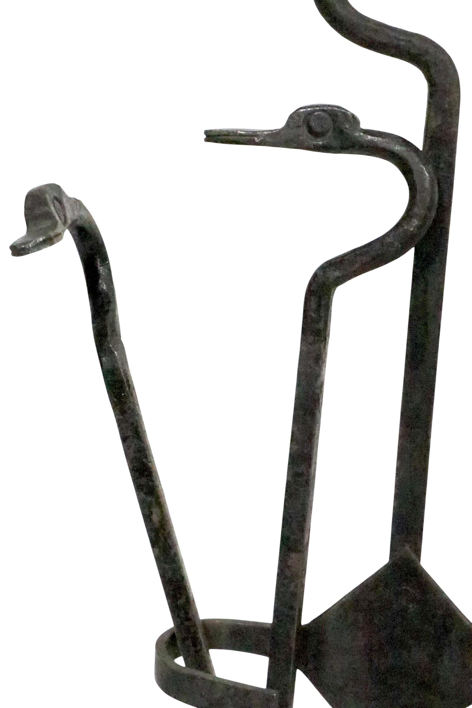 Insolito set di attrezzi da caminetto battuti a mano composto da attizzatoio, pinza, pala e supporto.  Il set è caratterizzato da una testa di uccello a becco lungo di profilo come manici, ed è in ottime condizioni, originale, pulito e pronto