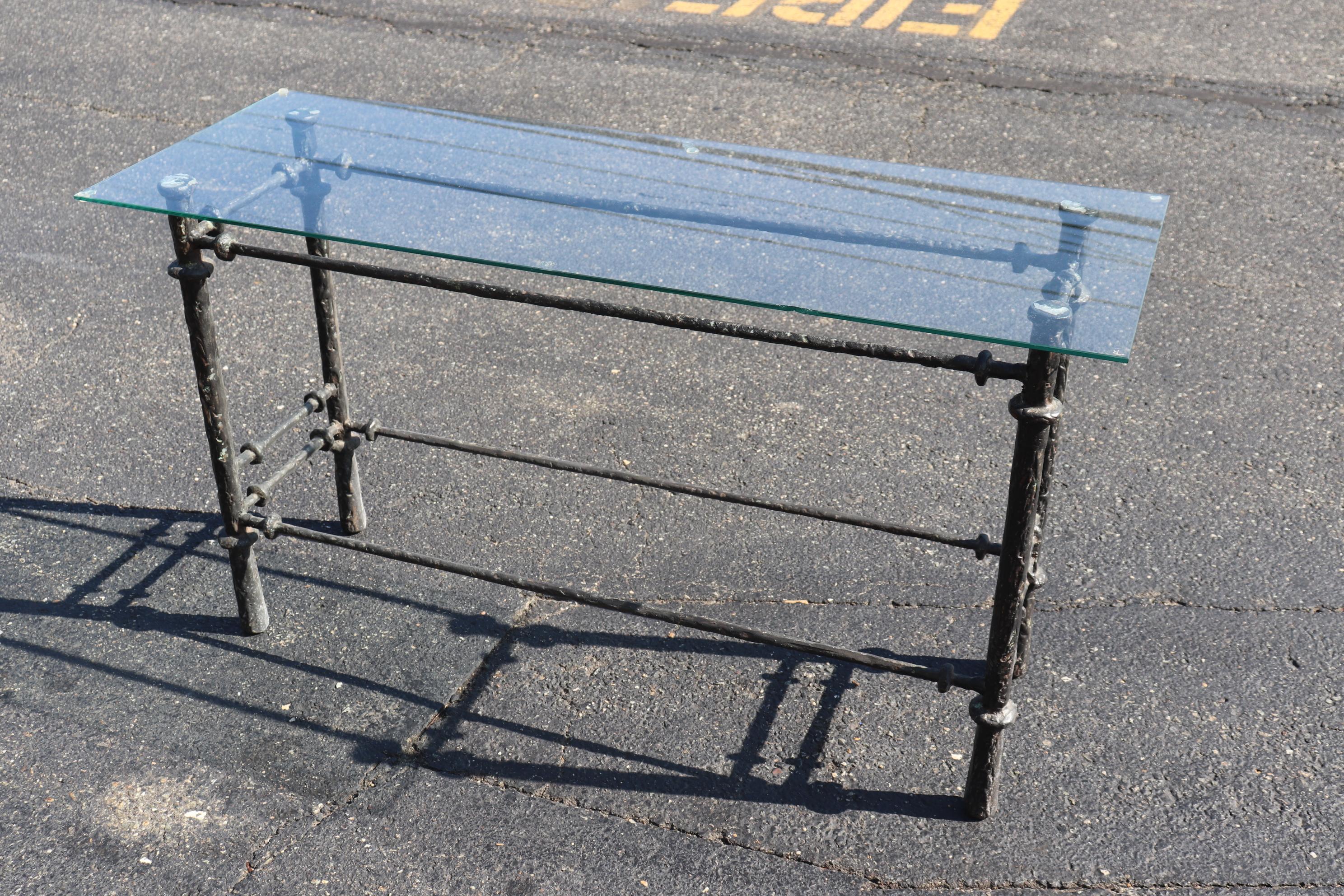 This is a unique Giacometti style wrought iron table with a plate glass top. The table base measures 42 x 13 deep x 26.75 tall and the table itself with the glass measures 48 wide x 17 deep x 27 tall. The table dates to the 1970s era and would look