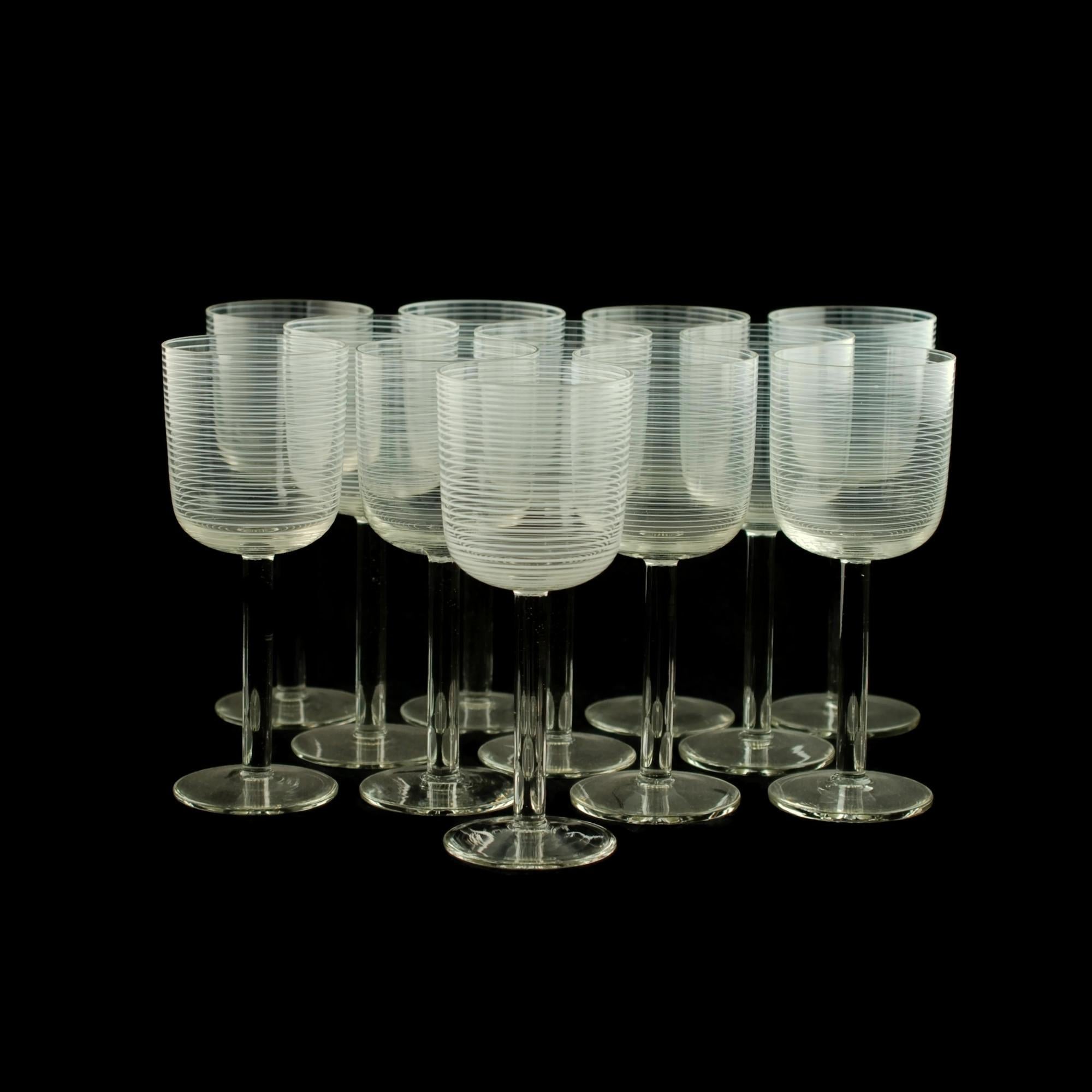 This elegant set of 12 handblown clear crystal goblets feature bowls which have been decorated with opaque white glass threads. The threads extend from the bottom of the bowls and spiral around the exterior, forming a series of closely spaced
