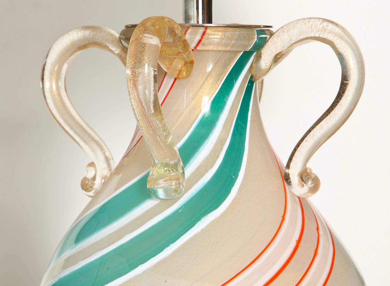 Bulbous form with interior gold inclusions and diagonal stripes of white, aqua and red. Applied hands and trim at top and bottom. White lacquered wood pedestal base.