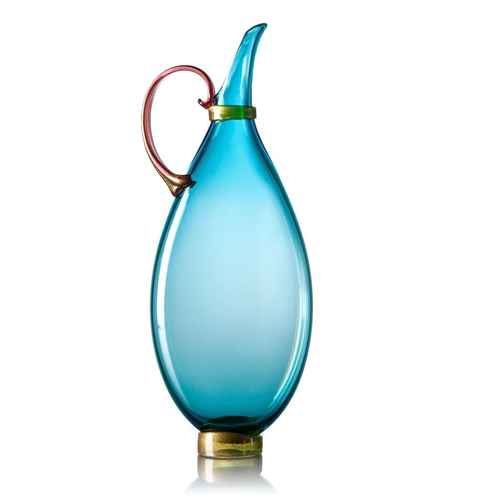 Designed to fit on narrow mantles, ledges and window sills, the contemporary petite copper blue flat pitcher is blown and pressed by hand during the glassblowing process to inspire displays layered with translucent color. A sculpted handle, wrap,