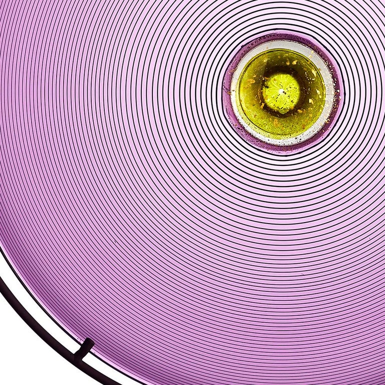 A luminous sculptural statement in Amethyst hand blown glass, the circular color wheel sculpture is blown and expanded to create an ecliptic disc form. Presented on a sturdy hand-fabricated metal Stand, the purple sculpture is made-to-order and