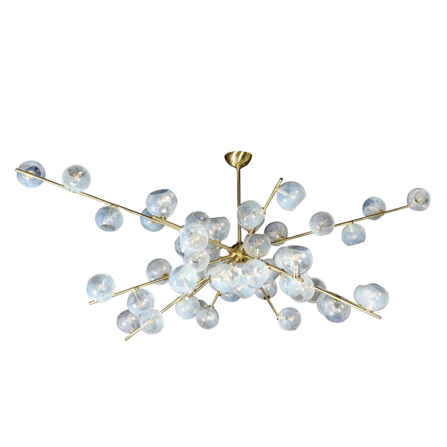 This stunning and monumental modernist chandelier is hand blown and handcrafted. It features an abundance of organic hand blown iridescent shades- each uniquely formed- attached to brass arms that appear to 