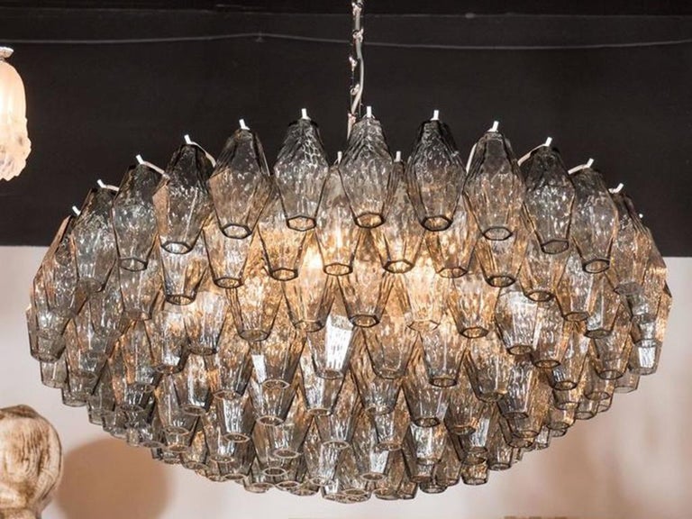 This impressive Murano glass chandelier, in the manner of Venini, features a constellation of handblown Murano glass polyhedral glass shades in a smoked platinum grey hue. Each shade has been individually hung, by hand, from its frame. Additionally,