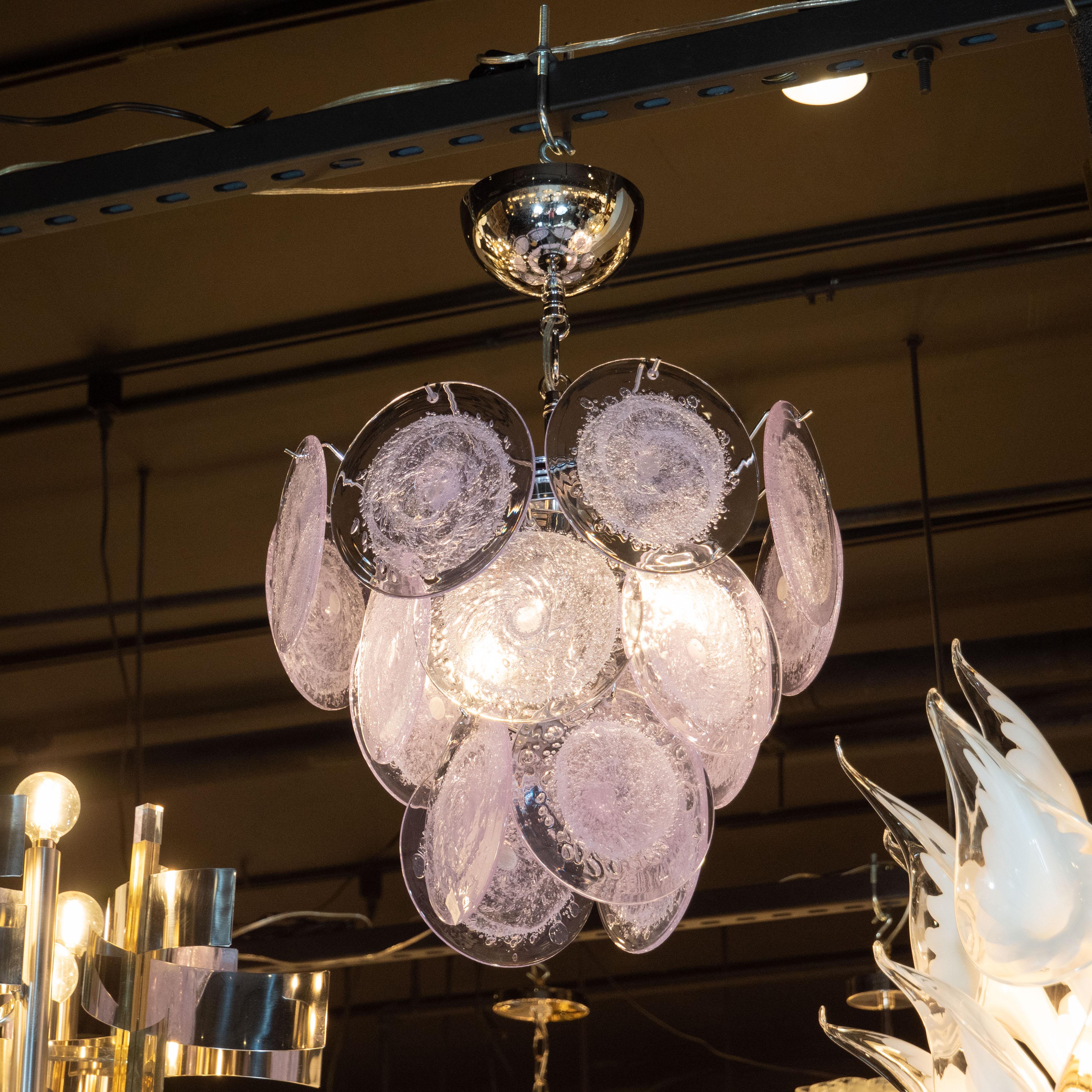 This chandelier has three descending tiers of translucent lavender discs, which are suspended from a polished chrome frame. Created in the manner of Vistosi, each disc is hand blown by artisans in Murano, Italy, the island off the coast of Venice