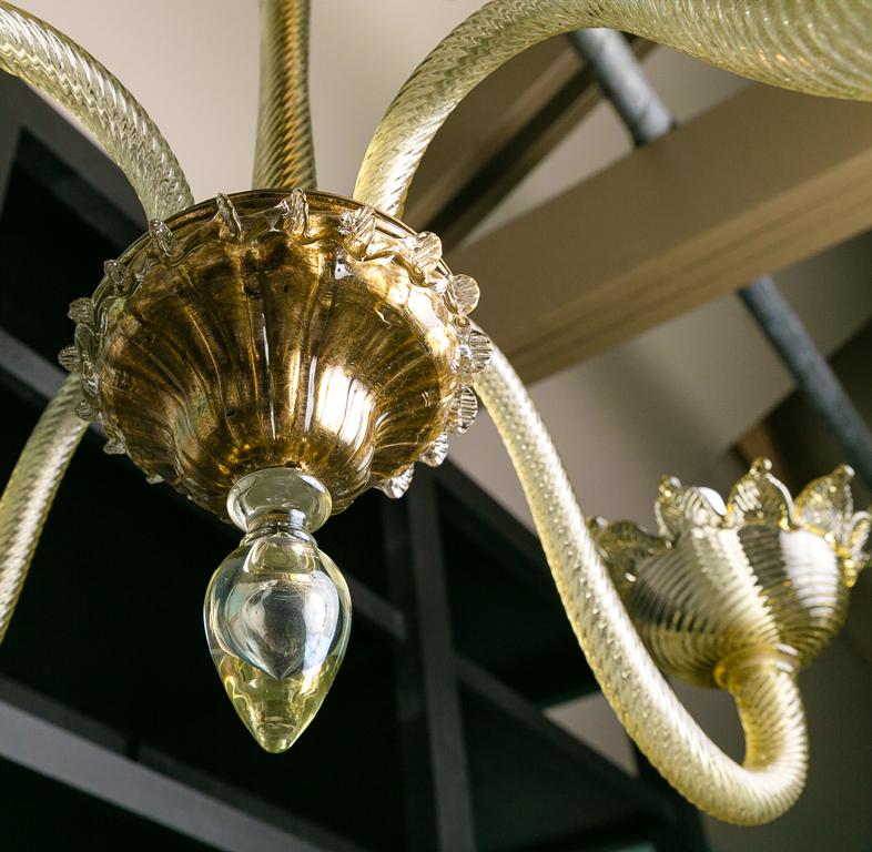 This elegant Murano chandelier has a tall stem and is simple and Classic. It has a subtle olivine color that is a bit chameleon-like in that it picks up the colors of a room.