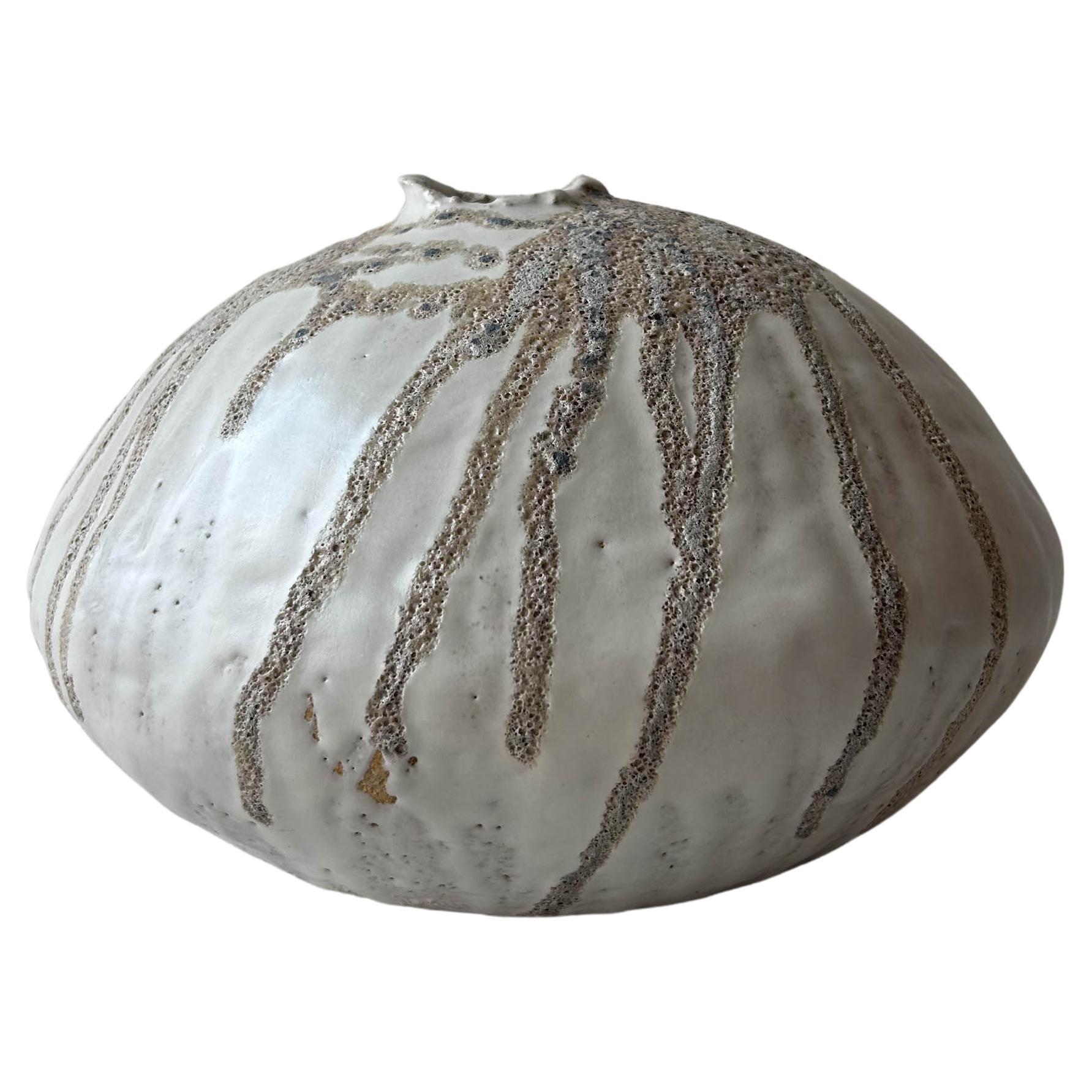 Vaso moderno organico costruito a mano con un corpo di argilla groggy ricoperto da strati di smalto bianco lucido e opaco, con uno smalto lavico fortemente strutturato sulla parte superiore. Ogni vaso è realizzato a mano nel nostro studio di