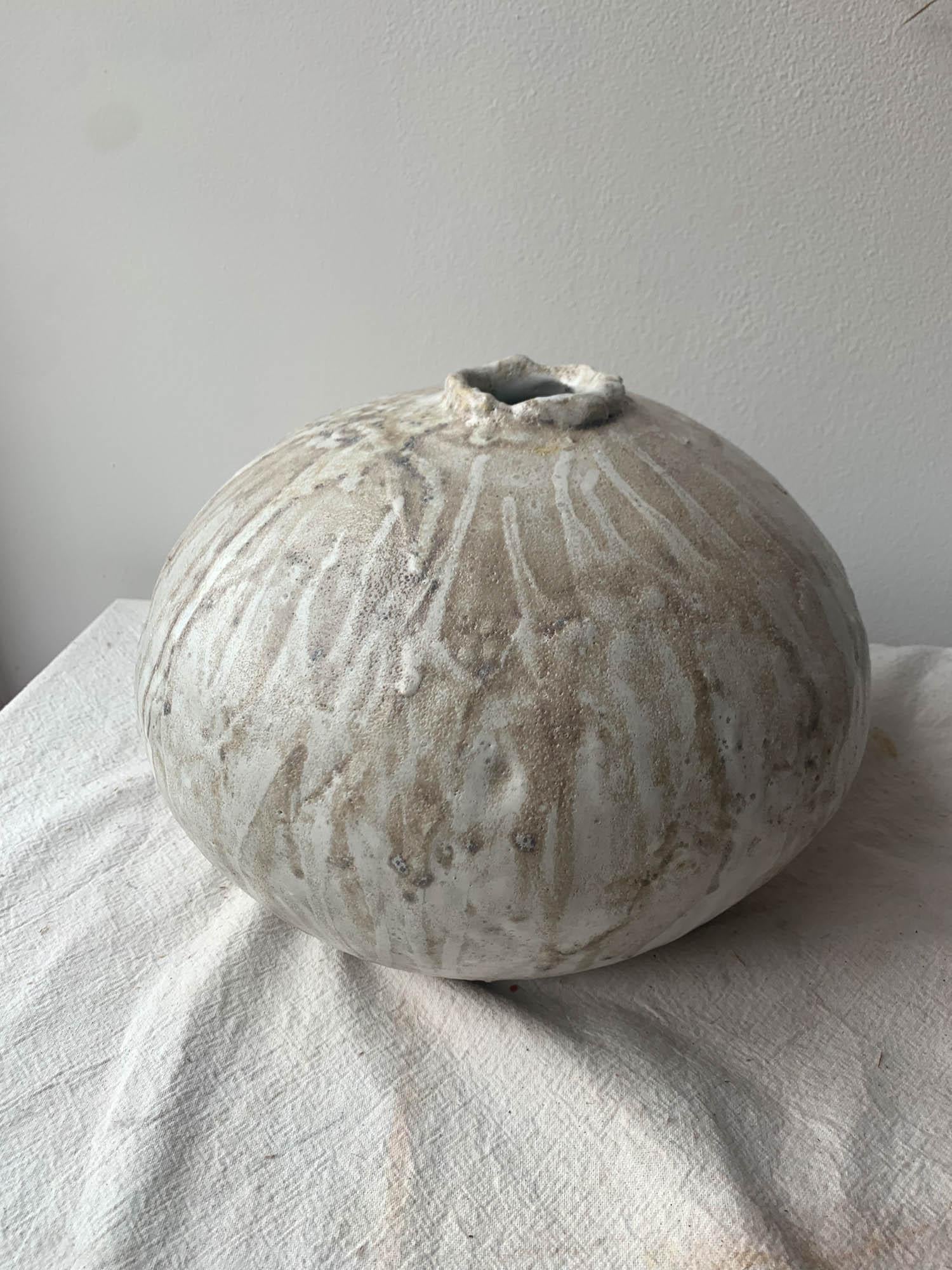 Handgefertigte, organisch-moderne Vase aus einem grobkörnigen Tonkörper, der mit Schichten aus glänzender und matter weißer Glasur überzogen ist, mit einer stark strukturierten Glasur obenauf. Jede Vase wird in unserem Studio in Brooklyn von Hand