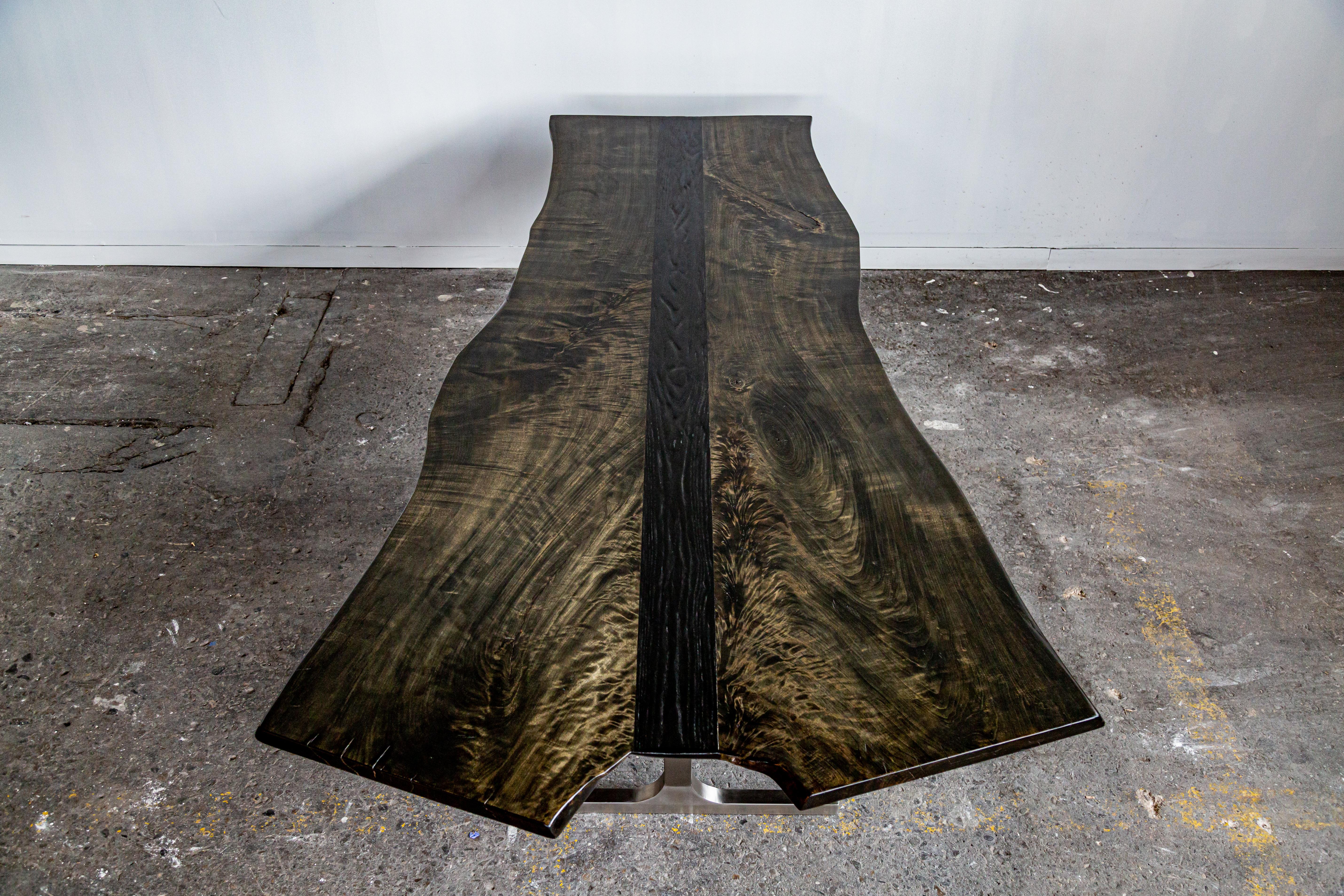 Handcrafted, natural cottonwood and oak dining table. A synthesis of sophisticated luxury with raw natural beauty. The dramatically oversized slab surface rests upon the stunning geometry of the hand welded sainless steel base. A strip of wood inlay