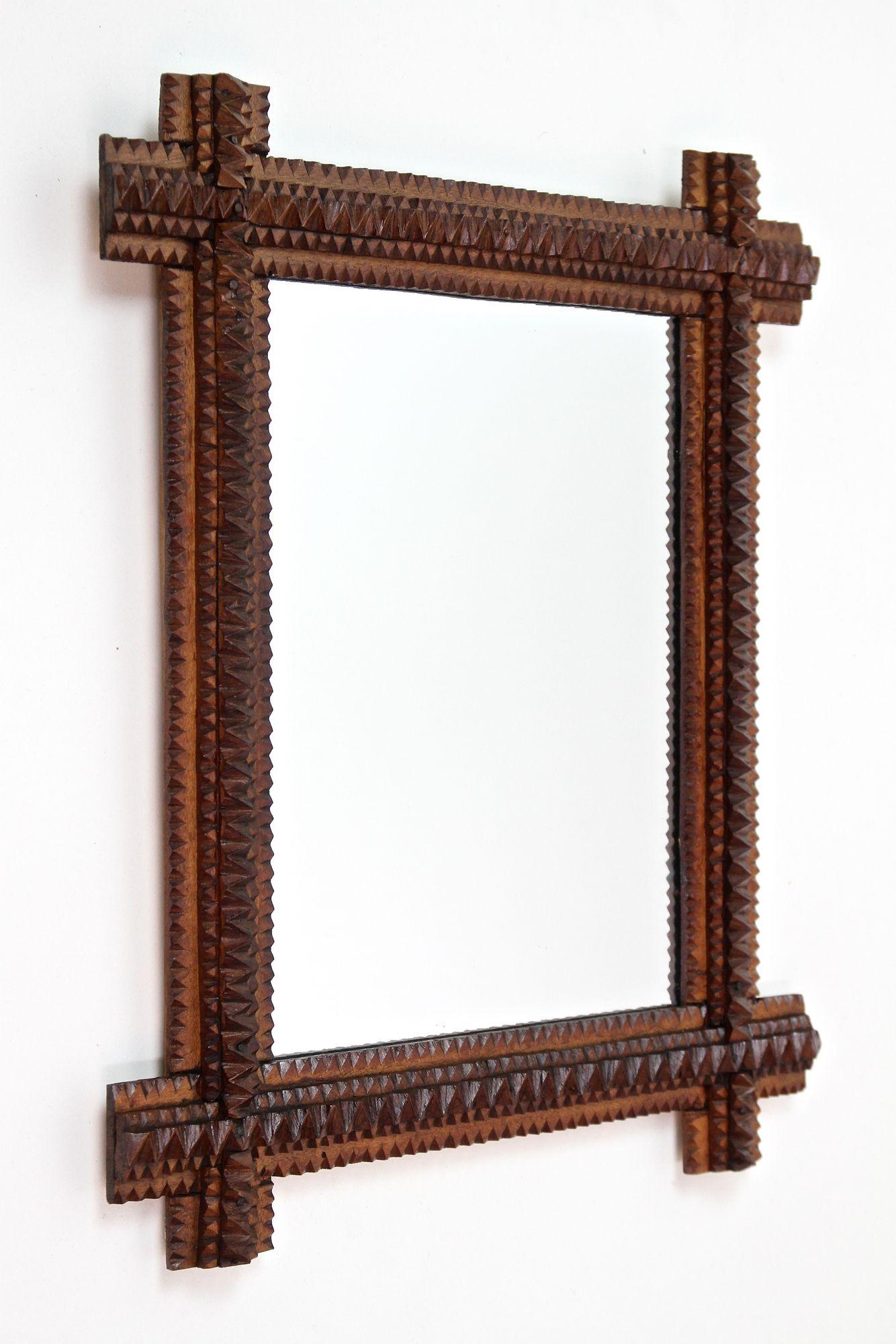 Exceptional rustic Tramp Art mirror from the period around 1880 in Austria. Elabortely hand-carved out of basswood, this lovely small wall mirror convinces with its great looking variety of different carving techniques. Slightly protruding corners