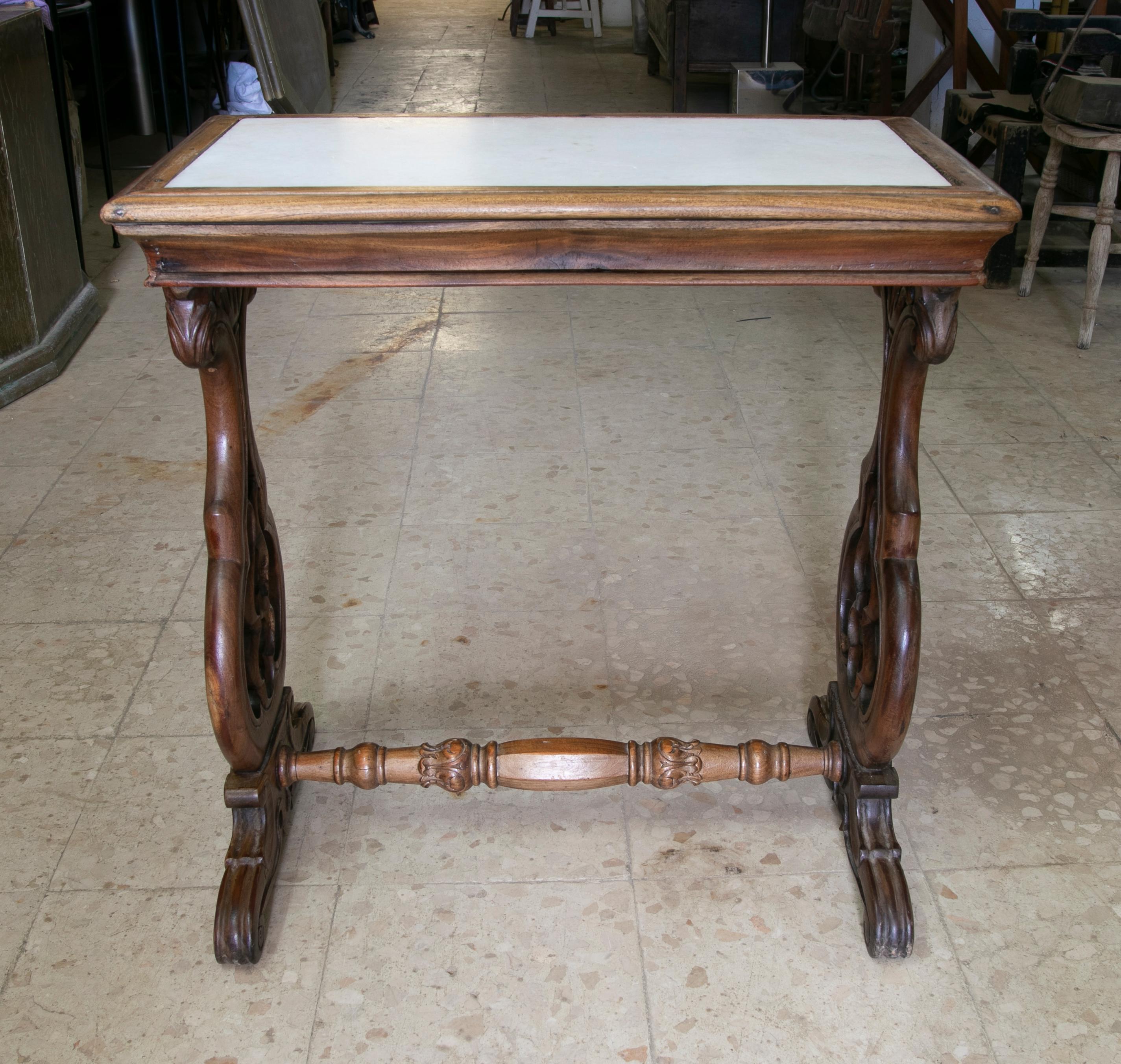 Handcarved wooden table with inlaid marble top.