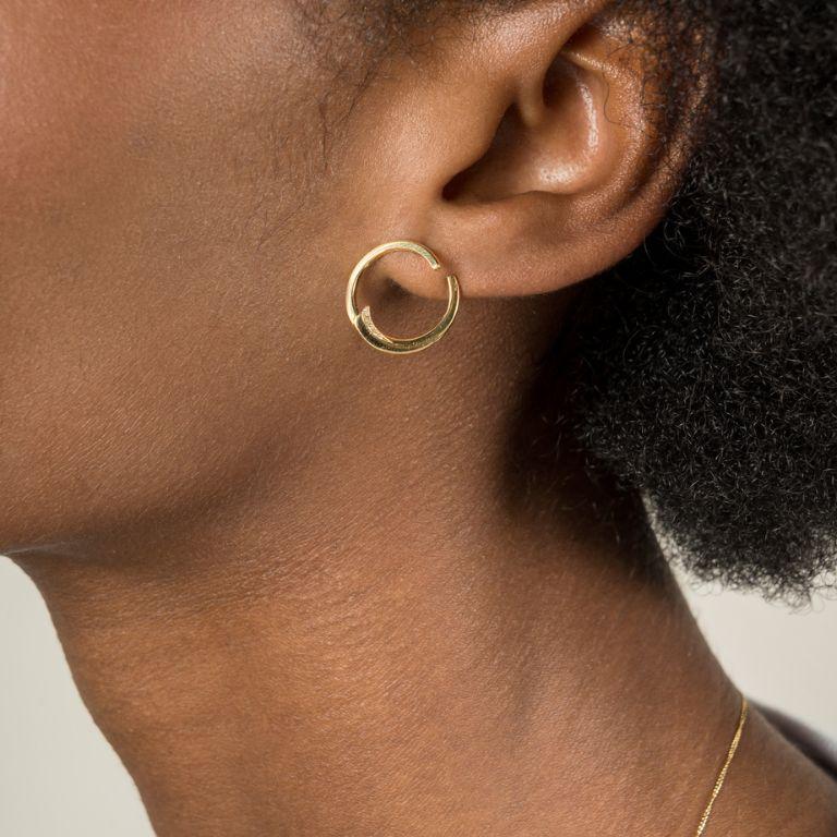 Questi moderni orecchini a cerchio in oro, progettati per giocare con lo spazio e le linee, sono realizzati a mano in oro giallo 18 carati e impreziositi da diamanti brillanti incastonati che catturano la luce lateralmente. Ideali per chi apprezza i