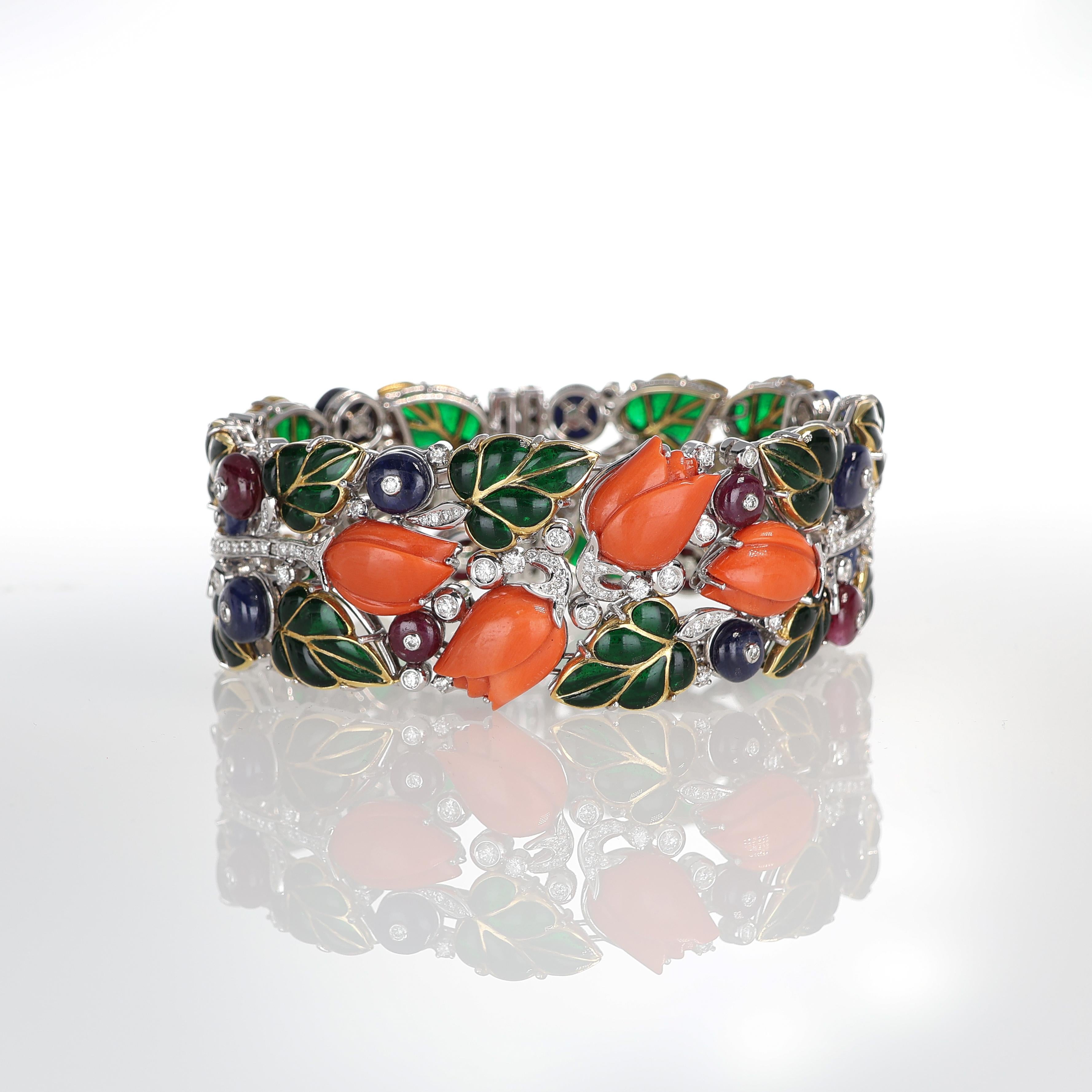 A masterpiece of fine craftsmanship, this handcrafted 18kt white gold rigid bracelet showcases an intricate floral-inspired design. Featuring natural emeralds, cabochon-cut sapphires and rubies, and brilliant-cut white diamonds, this piece exudes