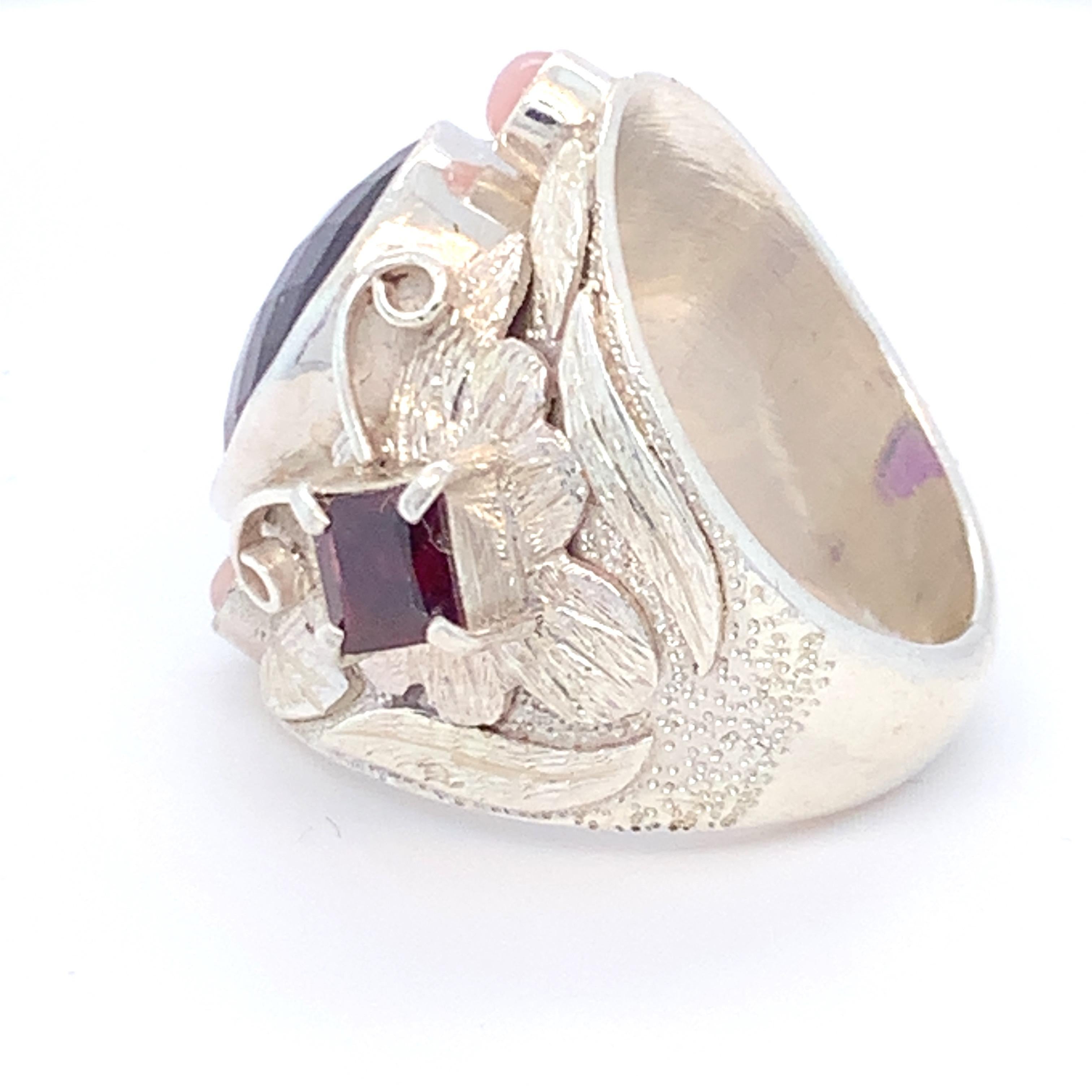 Checker board cut Amethyst is on the center of this stunning cocktail ring. It has square garnet on each side and round pink opal on top and bottom. Carefully made with hand in sterling silver.
Approximate size:
Amethyst: 8.0ct , 10 x 15mm
Pink