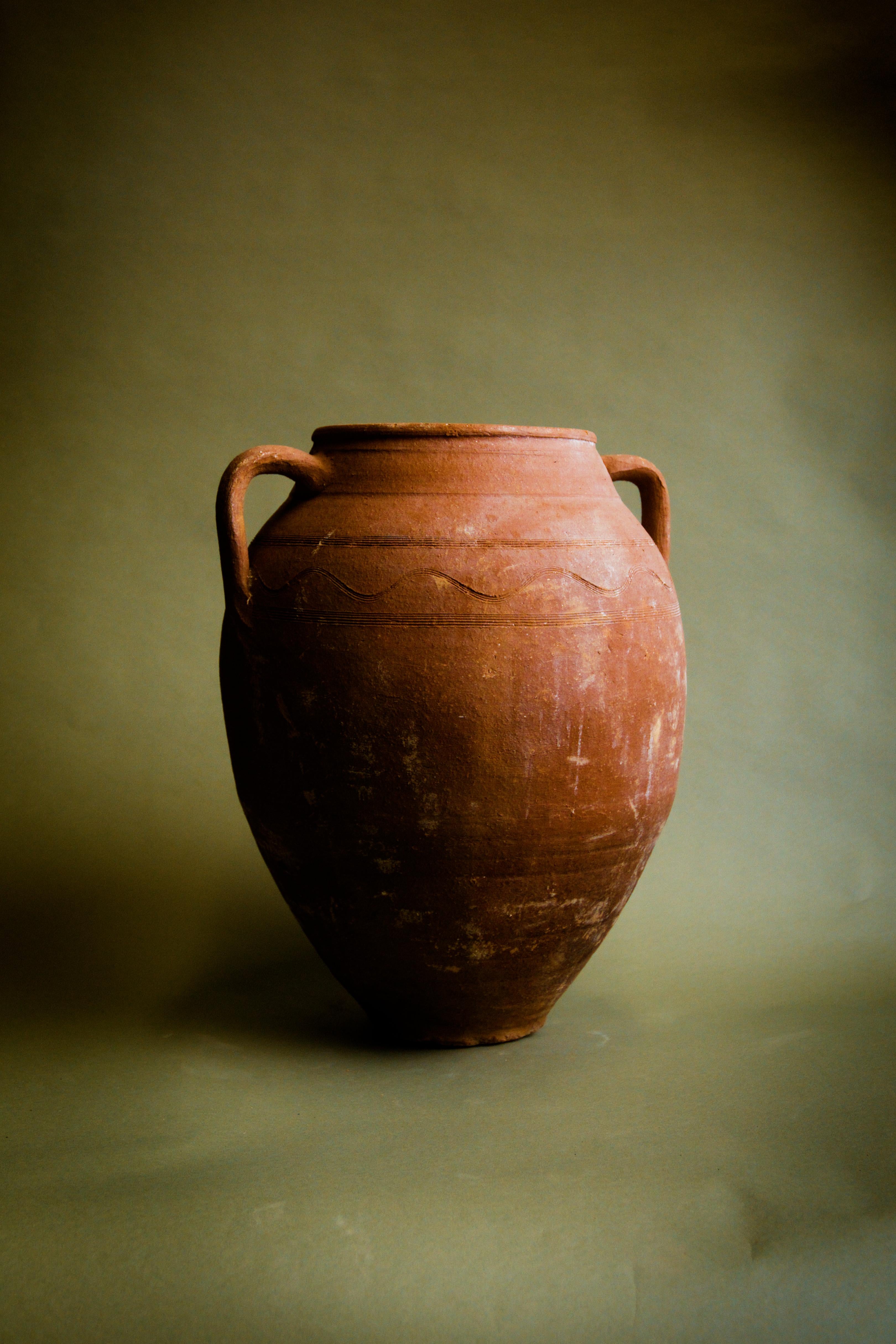 Scopri il fascino di questo recipiente vintage in terracotta anatolica, un vaso di argilla turca lavorato a mano che un tempo conservava cereali e provviste nelle case tradizionali dell'Anatolia. Ricco di significato storico, questo vaso rustico in