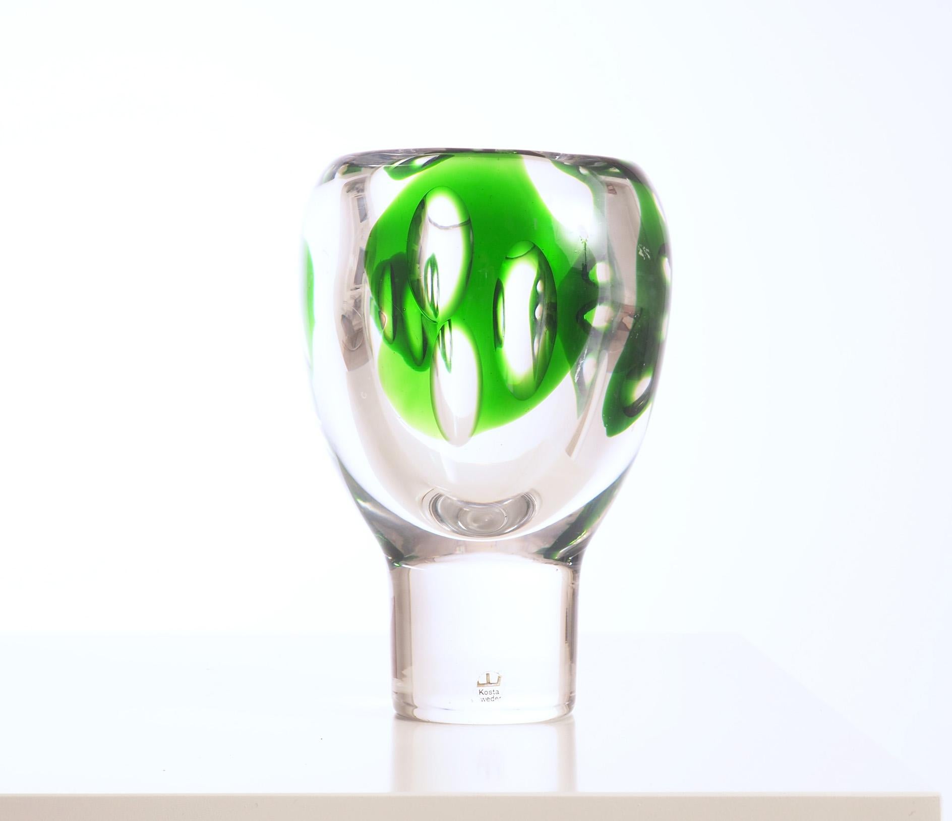 Vase by the Swedish glass artist Vicke Lindstrand. This piece was produced at Kosta during the 1950s and signed 46690 Lindstrand. The vase is in heavy glass, hand blown with inclosed green pattern and grinded for more optical effects.