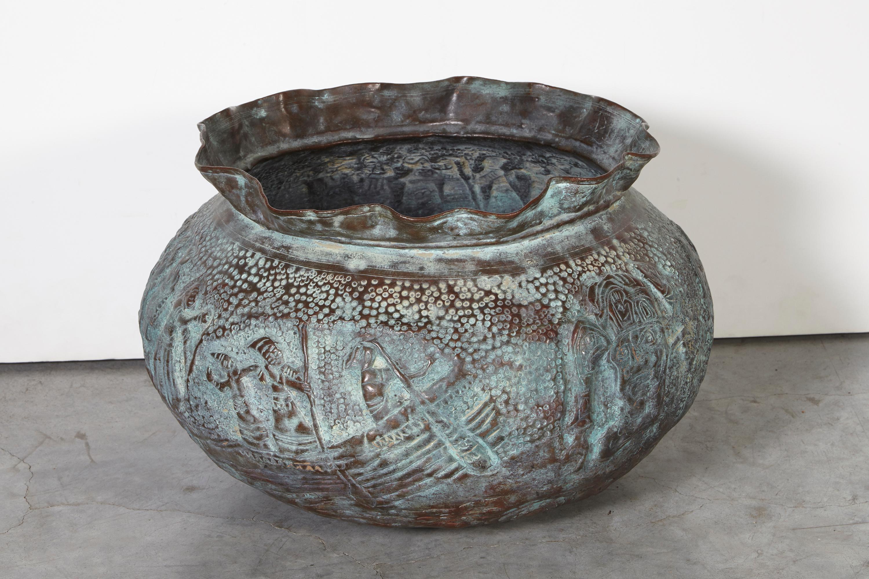 An expertly handcrafted copper repousse grain storage bowl with extraordinarily detailed images of folkloric figures from Bangladesh. The lovely soft green patina will complement any space. This is a really beautiful and unusual conversation