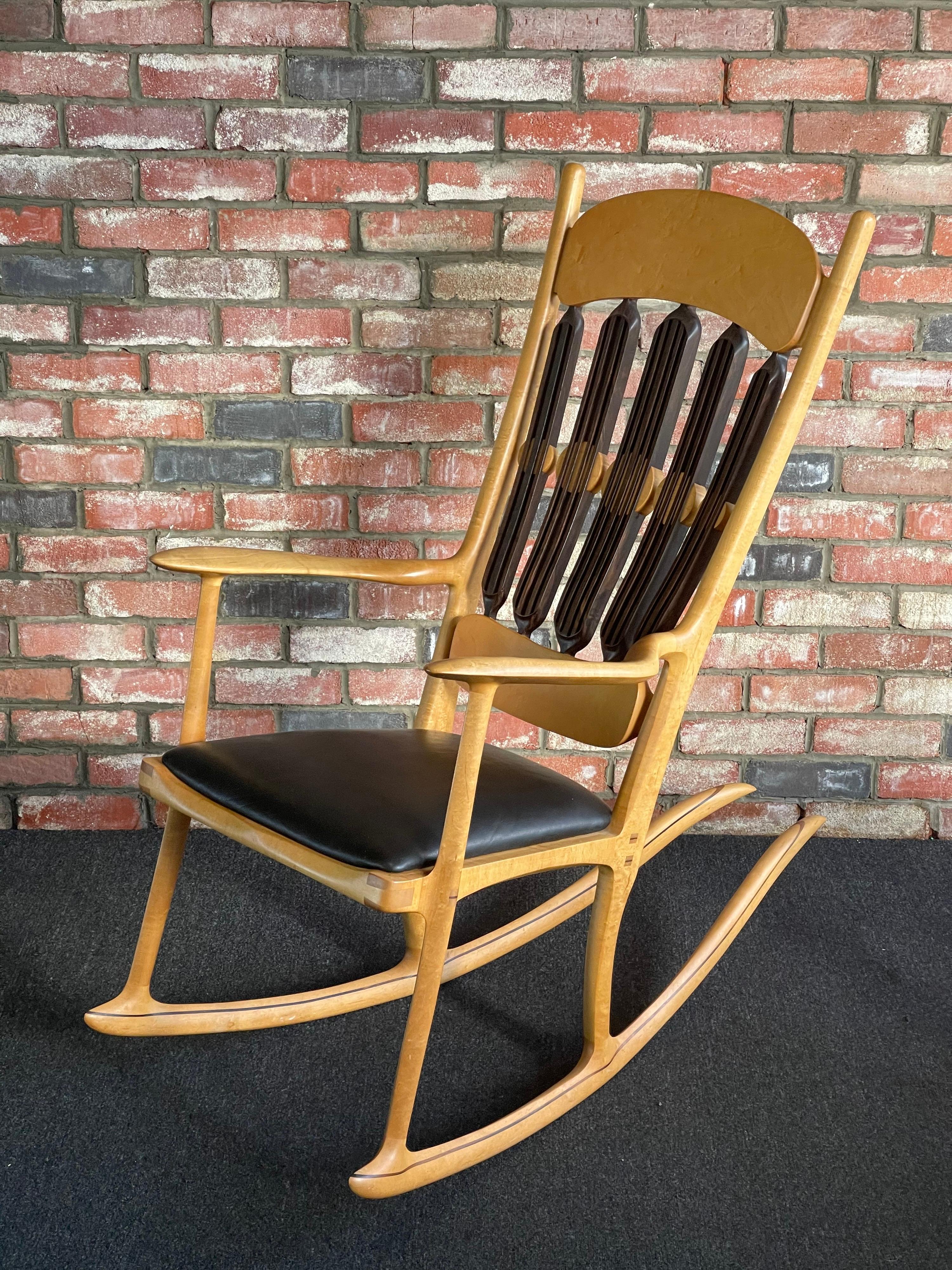 Gorgeous handcrafted artisan studio rocking chair by Jeffry Mann, circa 1987. This American made classic has a birds-eye maple frame with black walnut back spindles and striping; the seat is upholstered in black leather. The piece is an absolute