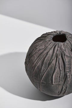 Vase en céramique noire artisanal avec motif de draperie texturé, finition mate