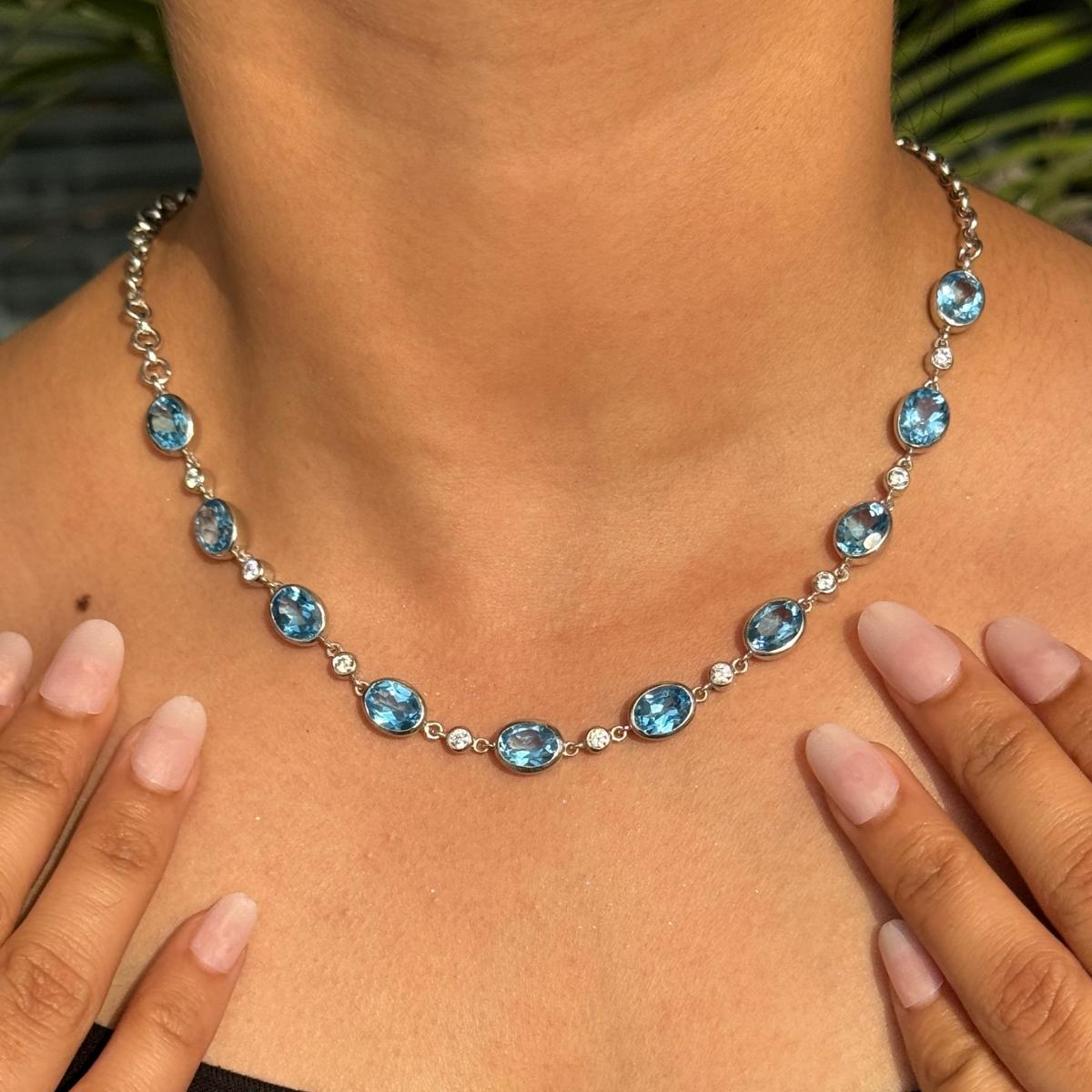 Questa collana artigianale a stazione con topazio blu e zircone è una squisita collana a stazione, realizzata in pregiato argento sterling 925. Caratterizzata da una serie di vivaci gemme di topazio blu dal taglio ovale, ciascuna incastonata a