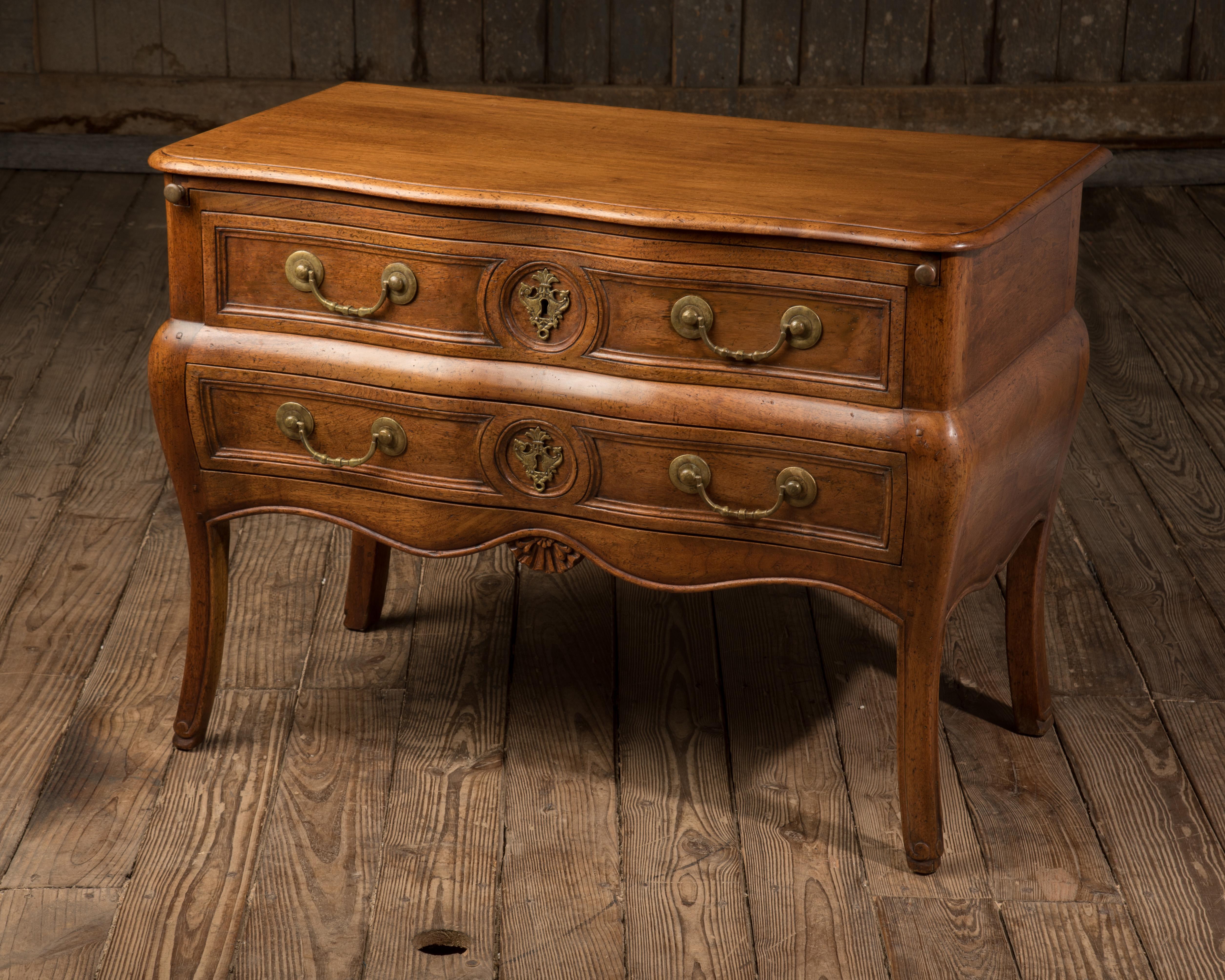 Very handsome beautifully crafted two-drawer commode in solid walnut by master cabinetmaker Don Ruseau, having hand-forged original brass hardware and lovely carving. Pull-out flat surface for extra space to lay out the newspaper or breakfast in