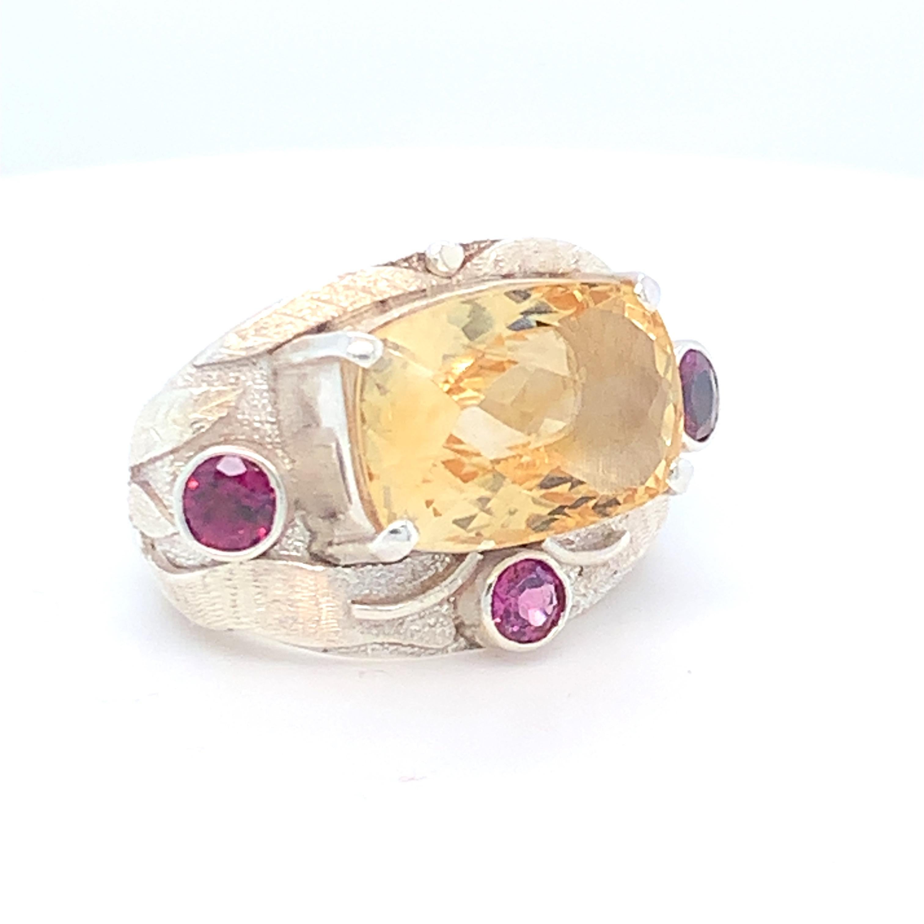 Checkerboard citrine is the main stone in this beautiful cocktail ring. Round rhodolites are used on three sides of the main stone. Set in sterling silver and made by hand.
Approximate size:
Citrine: 11.00ct
Rhodolite: 0.75ct
