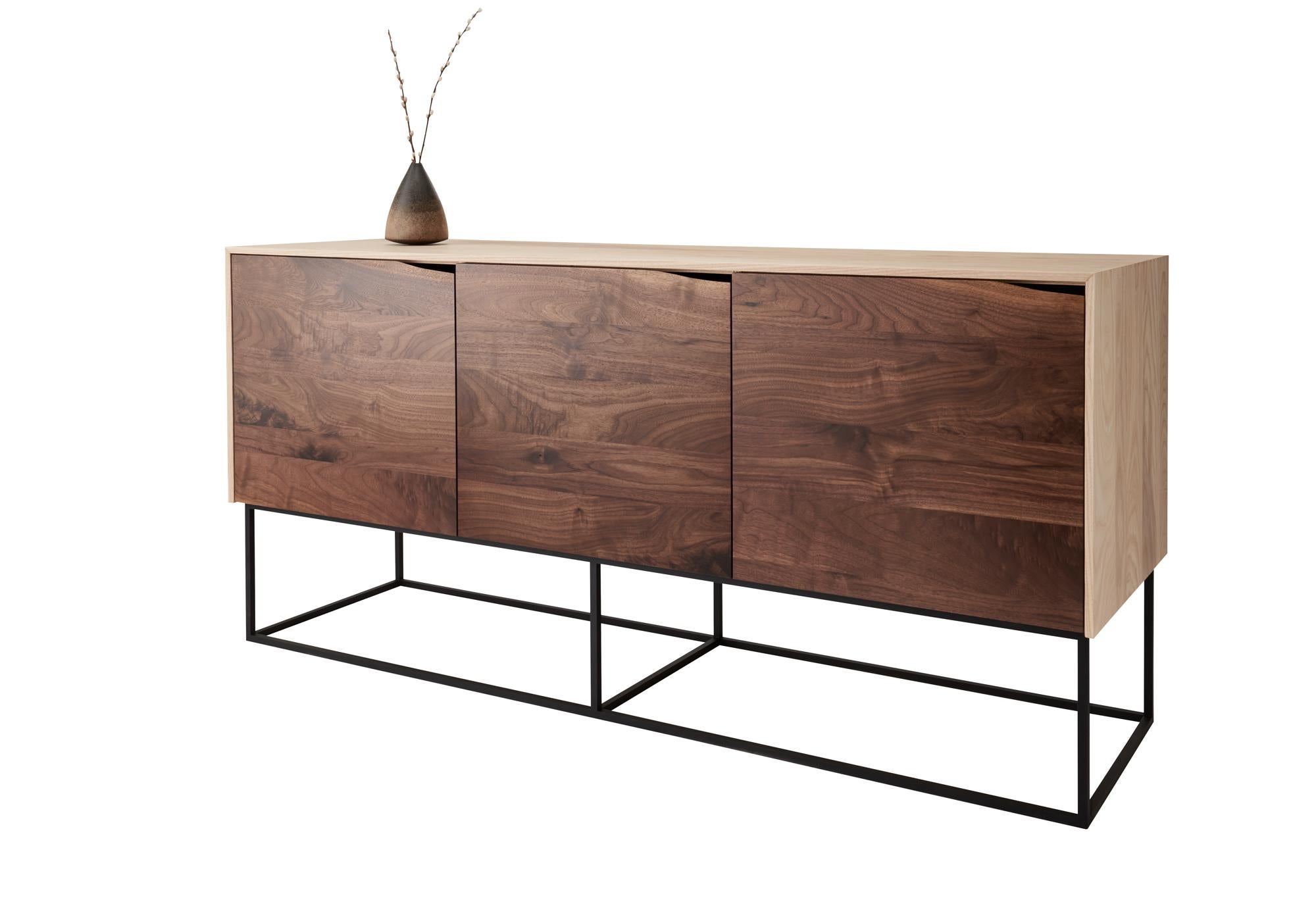 Handcrafted Classic modern credenza of natural ash and walnut with a cold-rolled steel base. The ash cabinet is coated with a no-VOC oil and wax finish leaving the wood with a raw look. The soft-close walnut doors are constructed from handcut veneer