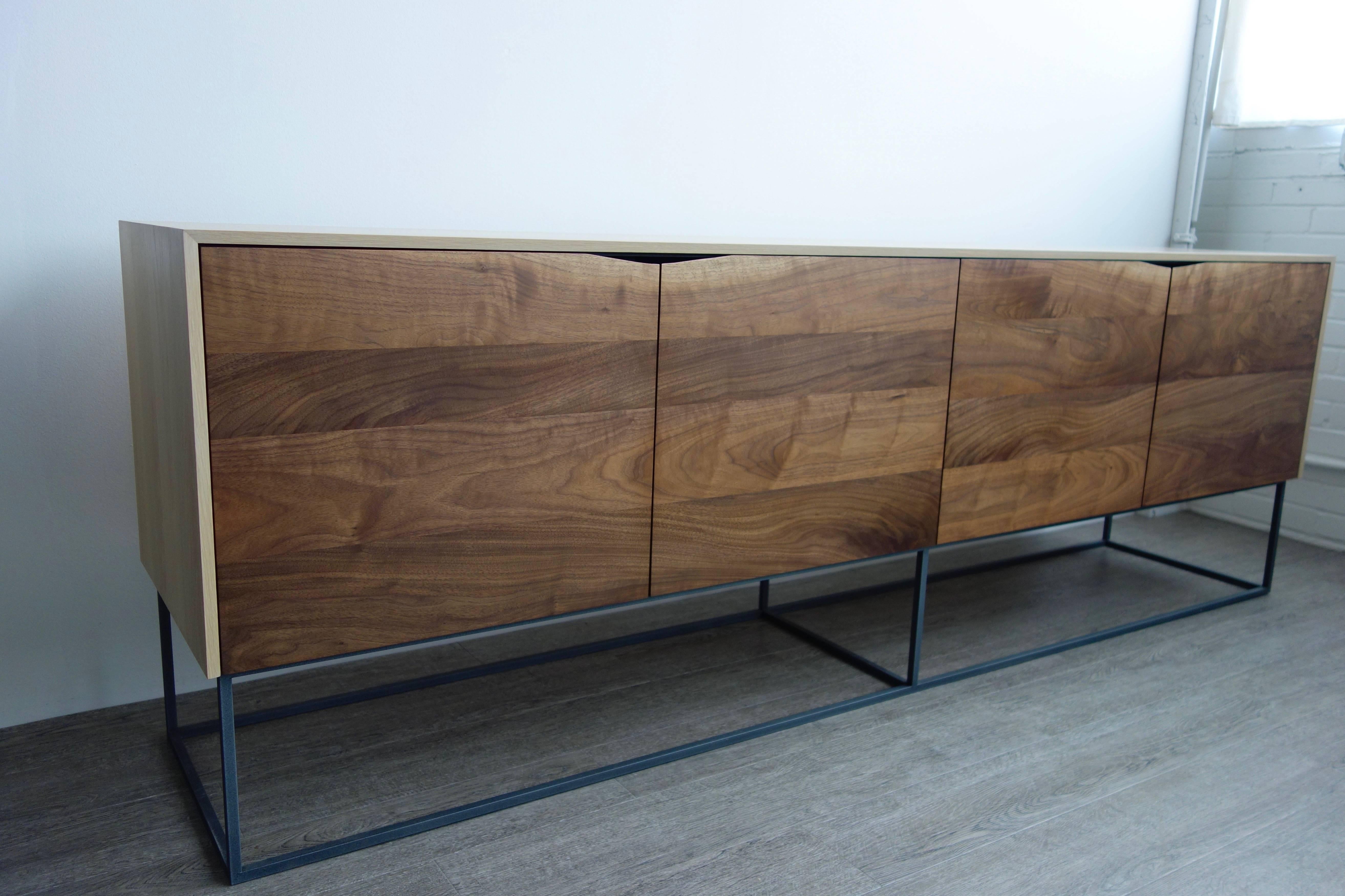 Handcrafted classic modern credenza of select white oak and walnut with a cold-rolled steel base. The exterior of the white oak cabinet is finished with a durable natural product that gives it a raw appearance; the interior is coated with a charcoal