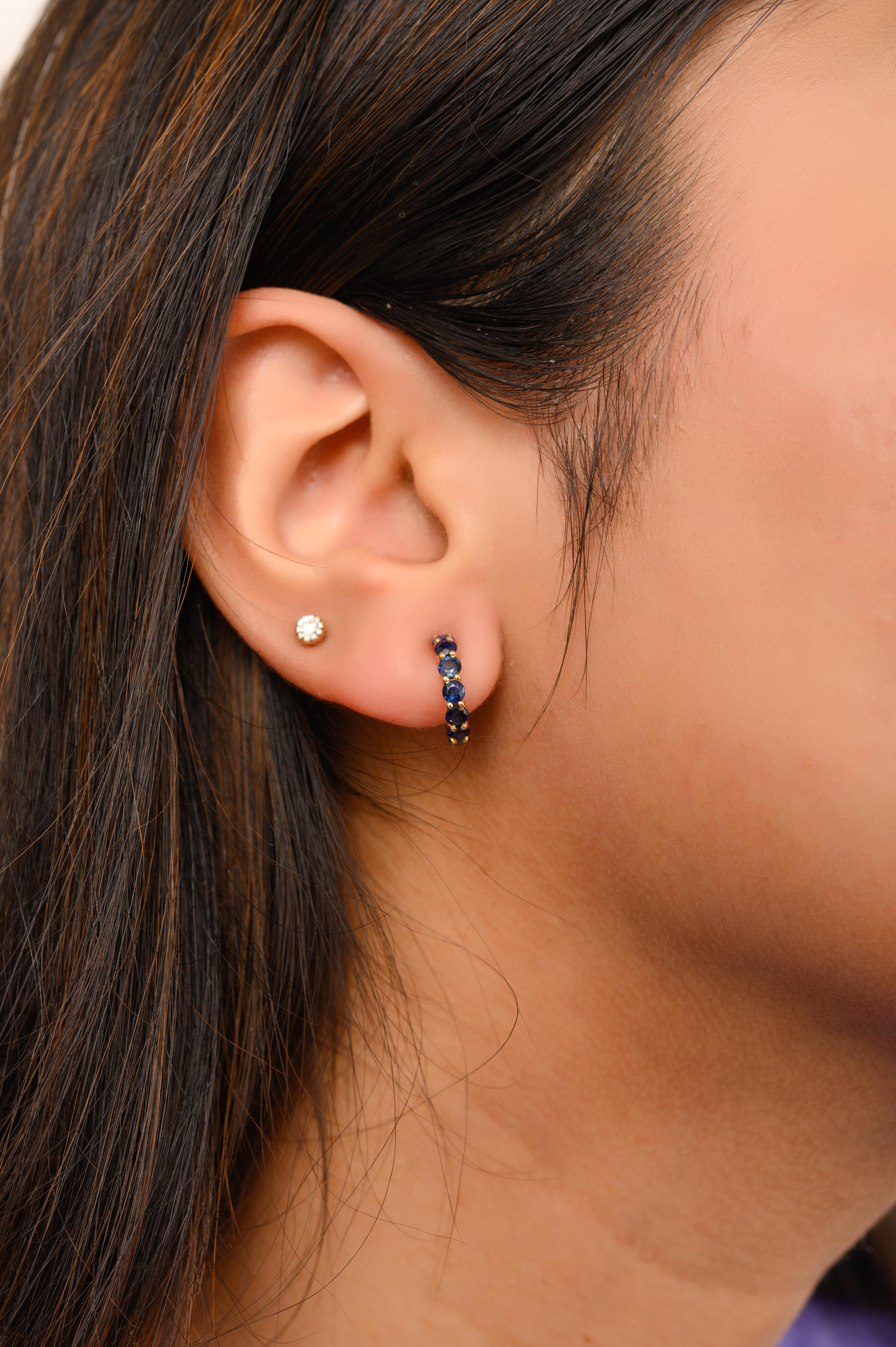 Handgefertigte zierliche blaue Saphir Huggie Hoop Earrings in 18K Gold, um Ihren Look zu unterstreichen. Um mit Ihrem Look ein Statement zu setzen, brauchen Sie Reifohrringe. Diese Ohrringe mit rund geschliffenen Saphiren sorgen für einen