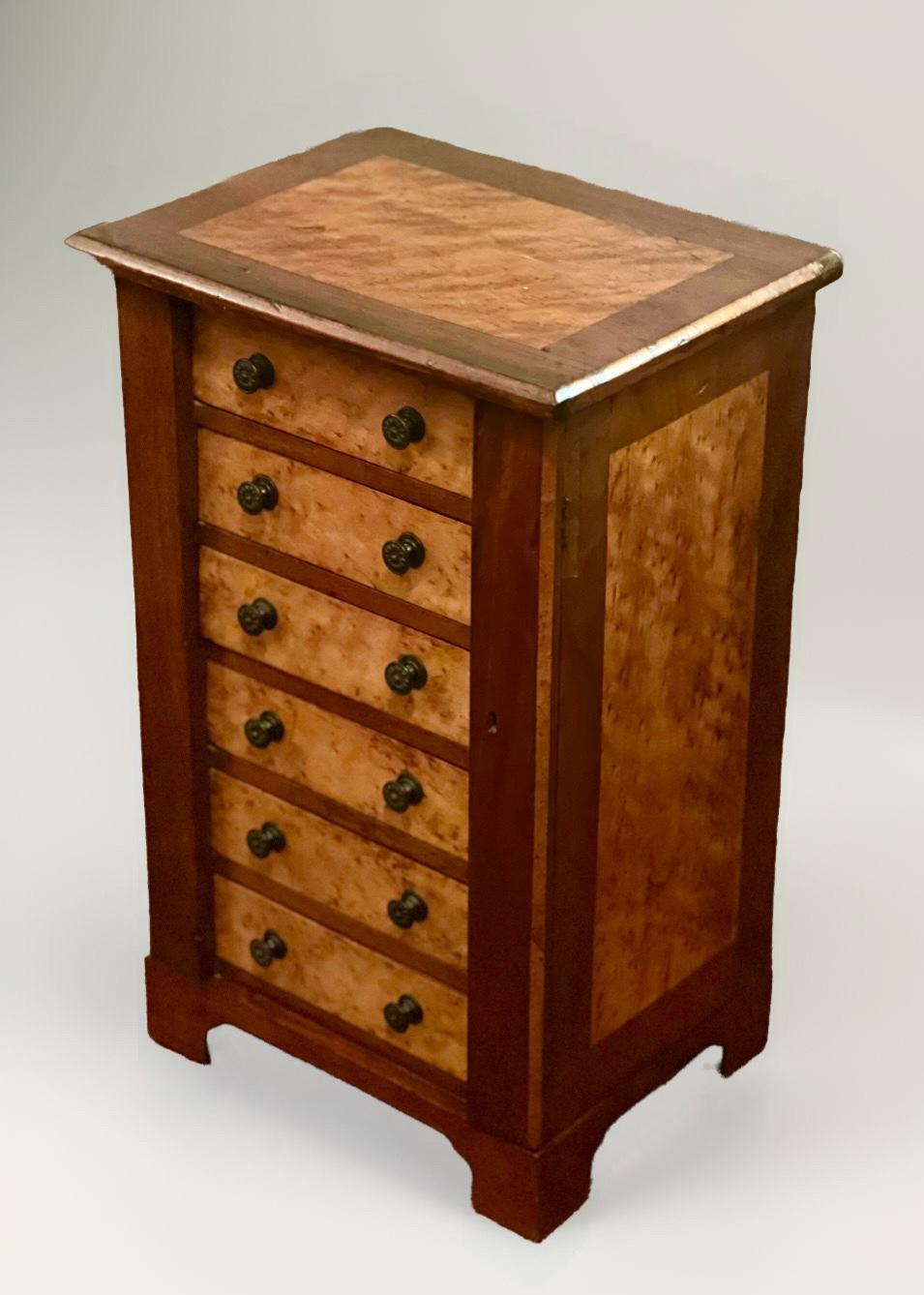 Mahogany and burl maple miniature Wellington chest, England, c. 1890-1900.

Rare, handcrafted petite chest with beautiful contrasting wood grains featuring six dovetailed drawers with rosette knobs, set upon bracket feet. Top drawer has
