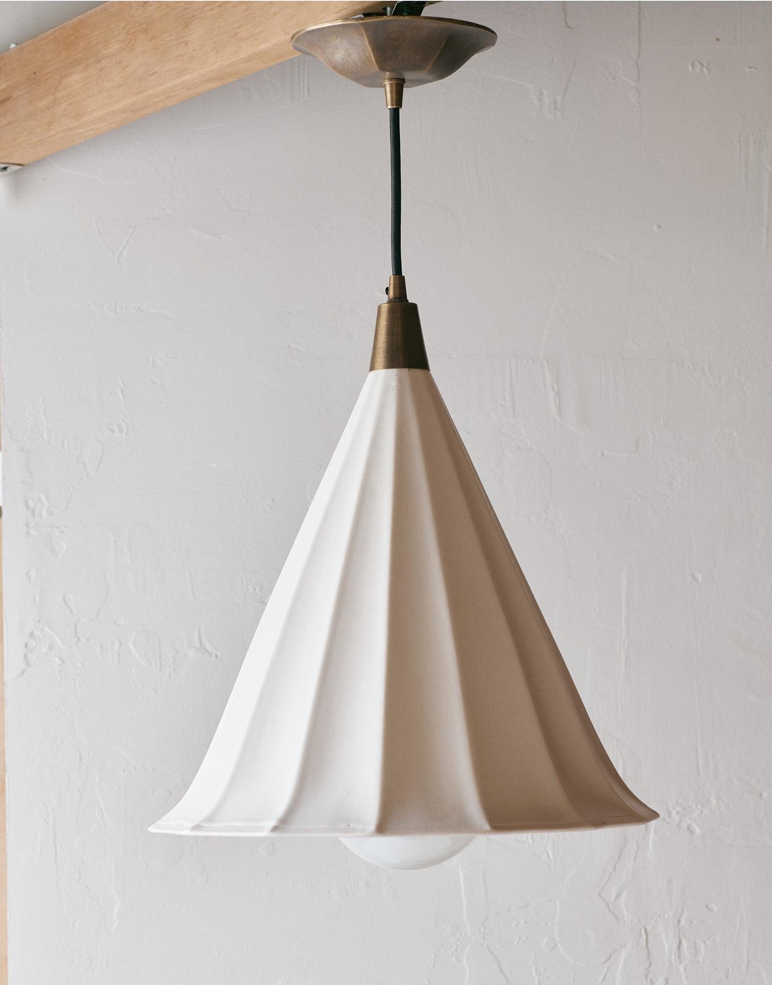 Classic, elegant, with a perfectly imperfect touch. On their own they make a statement with their gentle flared bottoms and deep fluting. Hang in multiples for extra oomph. These cast porcelain pendants include brass ceiling cap and hardware with