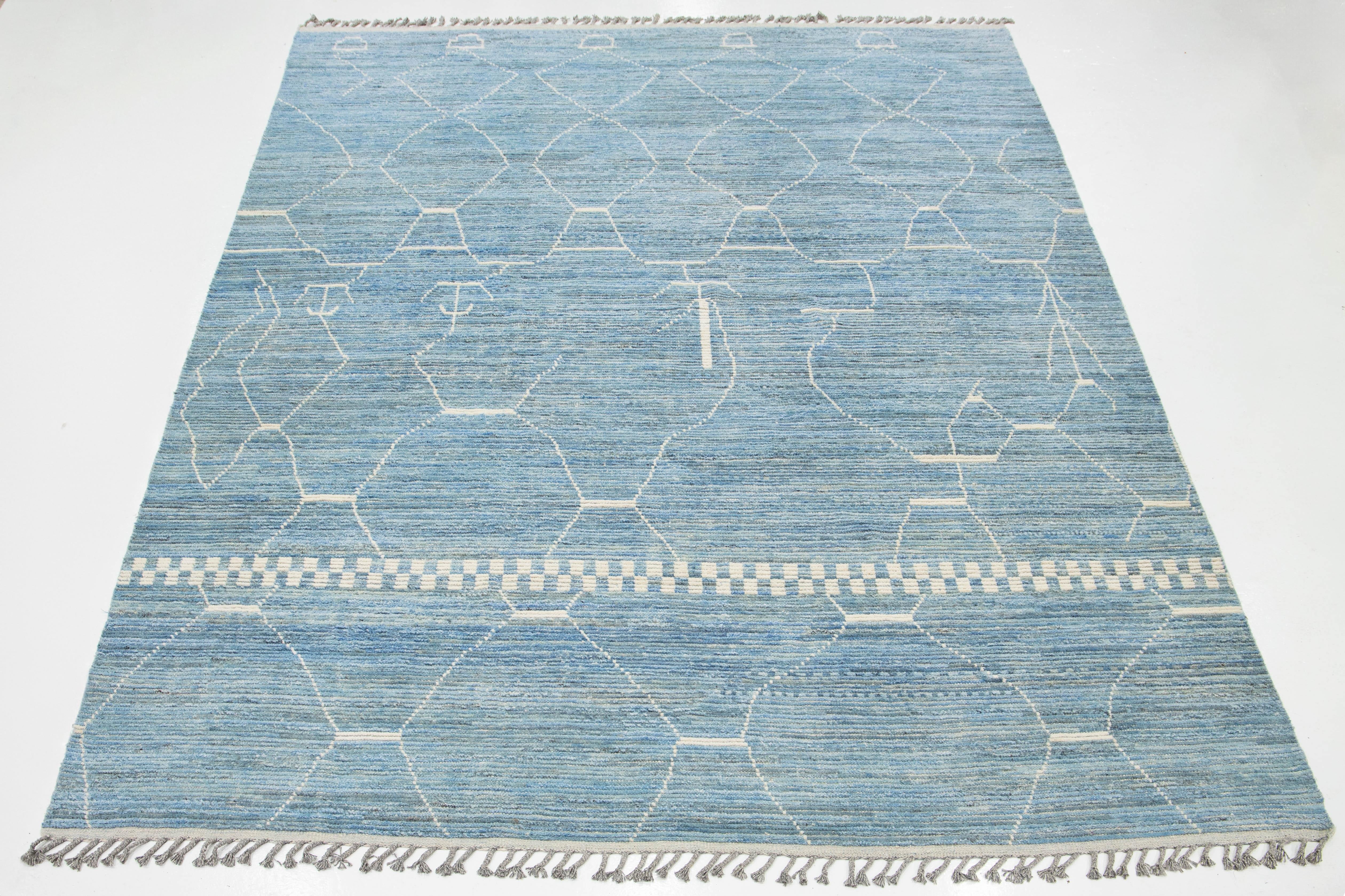 Élevez votre espace avec ce tapis fabriqué à la main et inspiré par le design marocain moderne. Confectionné en laine douce de première qualité, il présente un motif géométrique blanc saisissant sur fond bleu clair. Parfait pour les salons, les