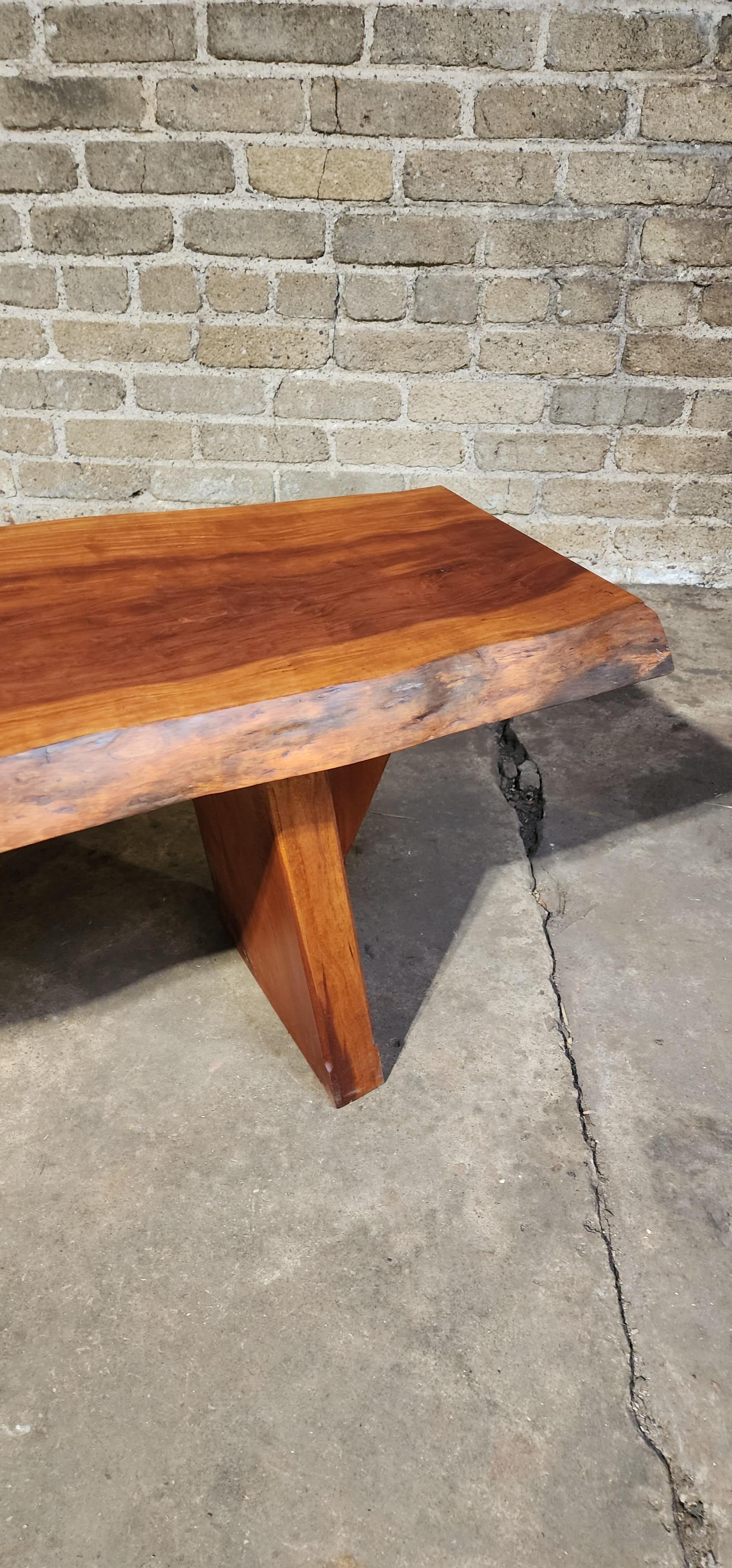 A finely made bench in solid cherry, created by a contemporary studio furniture maker, PJ Spring. known for warm natural materials and detailed handwork. The seat shows rich color variation and subtle grain movement typical of cherry that has begun