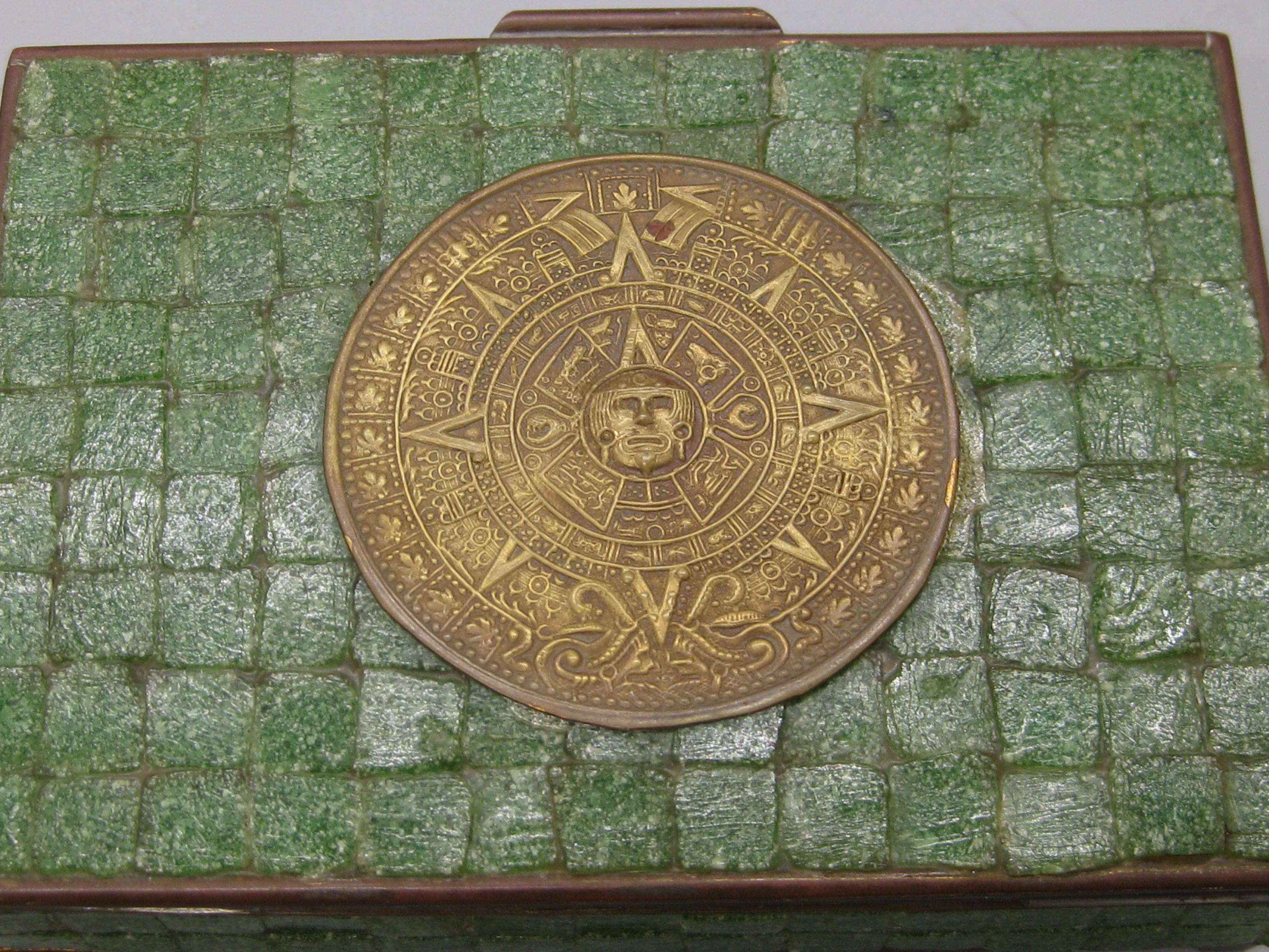 Preciosa tabaquera decorativa hecha a mano con incrustaciones de latón y azulejos de piedra. La caja tiene una forma y un diseño maravillosos. La parte superior tiene un calendario azteca de latón. Tiene una gran pátina y se puede pulir si se desea.