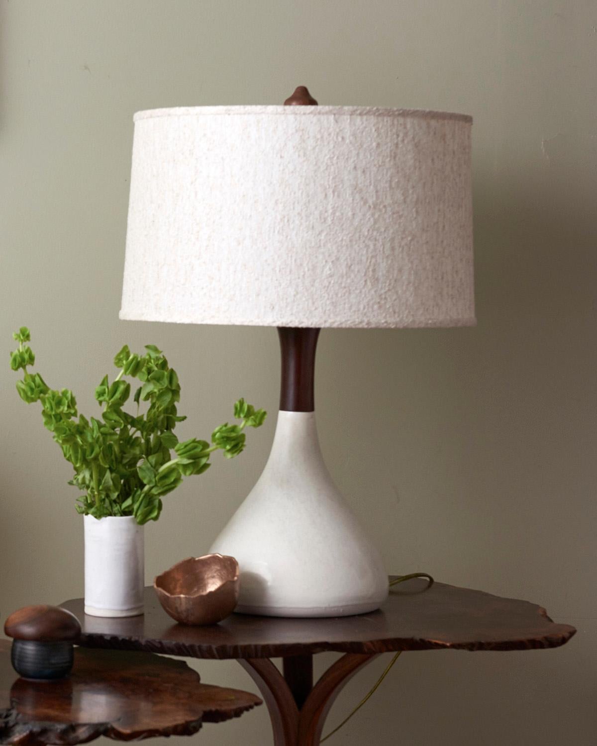 Meet Bella. Inspired by Mid-Century Modern design, Bella is both curvy and tapered, making her substantial but quite elegant. A hand poured porcelain base is topped with a hand turned walnut neck and finial. Nubbly boucle shade. Nickel hardware,