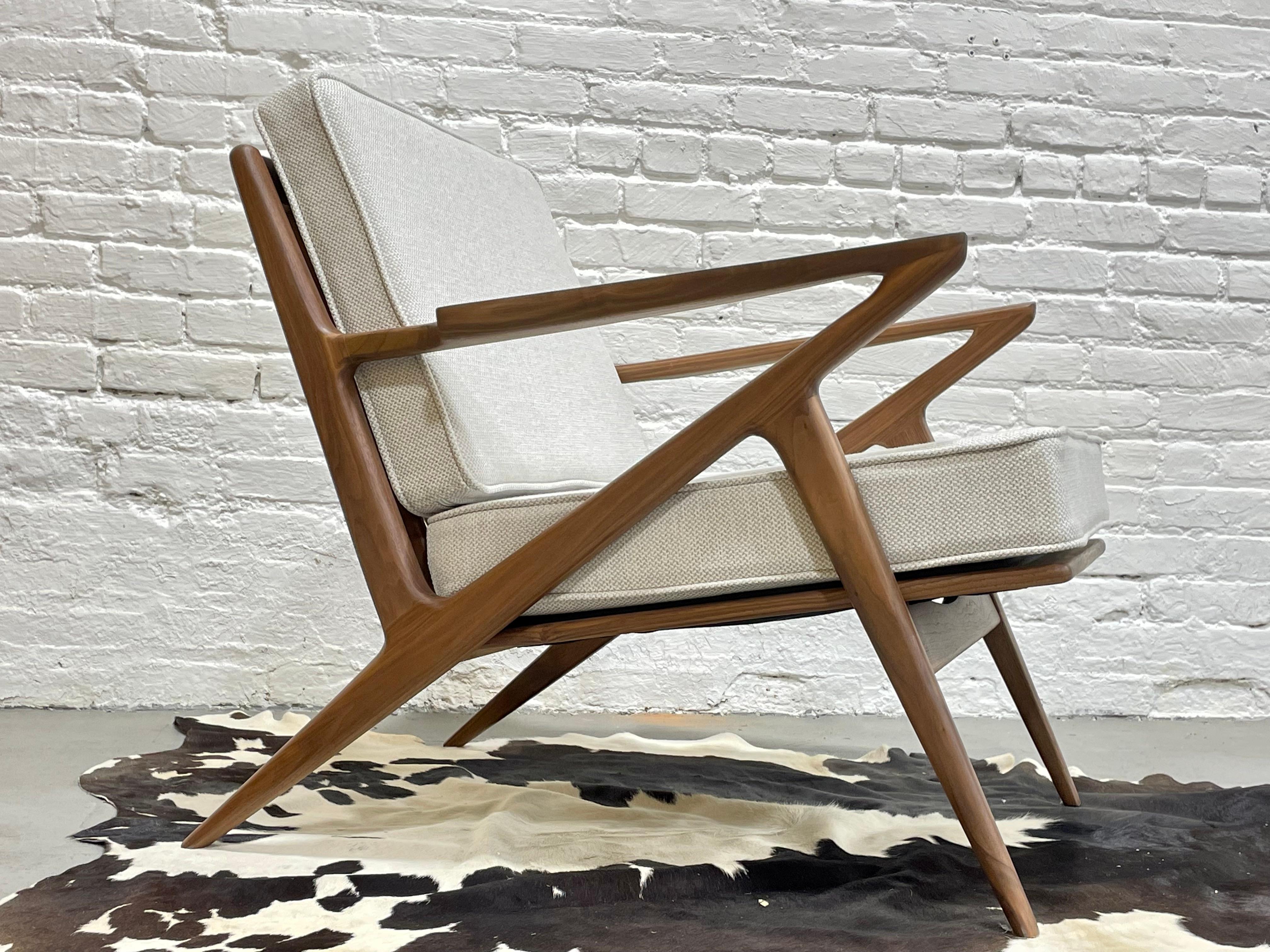 Mid Century Modern styled lounge chair, intricately handcrafted and designed in solid American Walnut. This incredible chair offers loads of design details such as sculptured armrests, triangular back slats and stunning wood grains. The cushions are