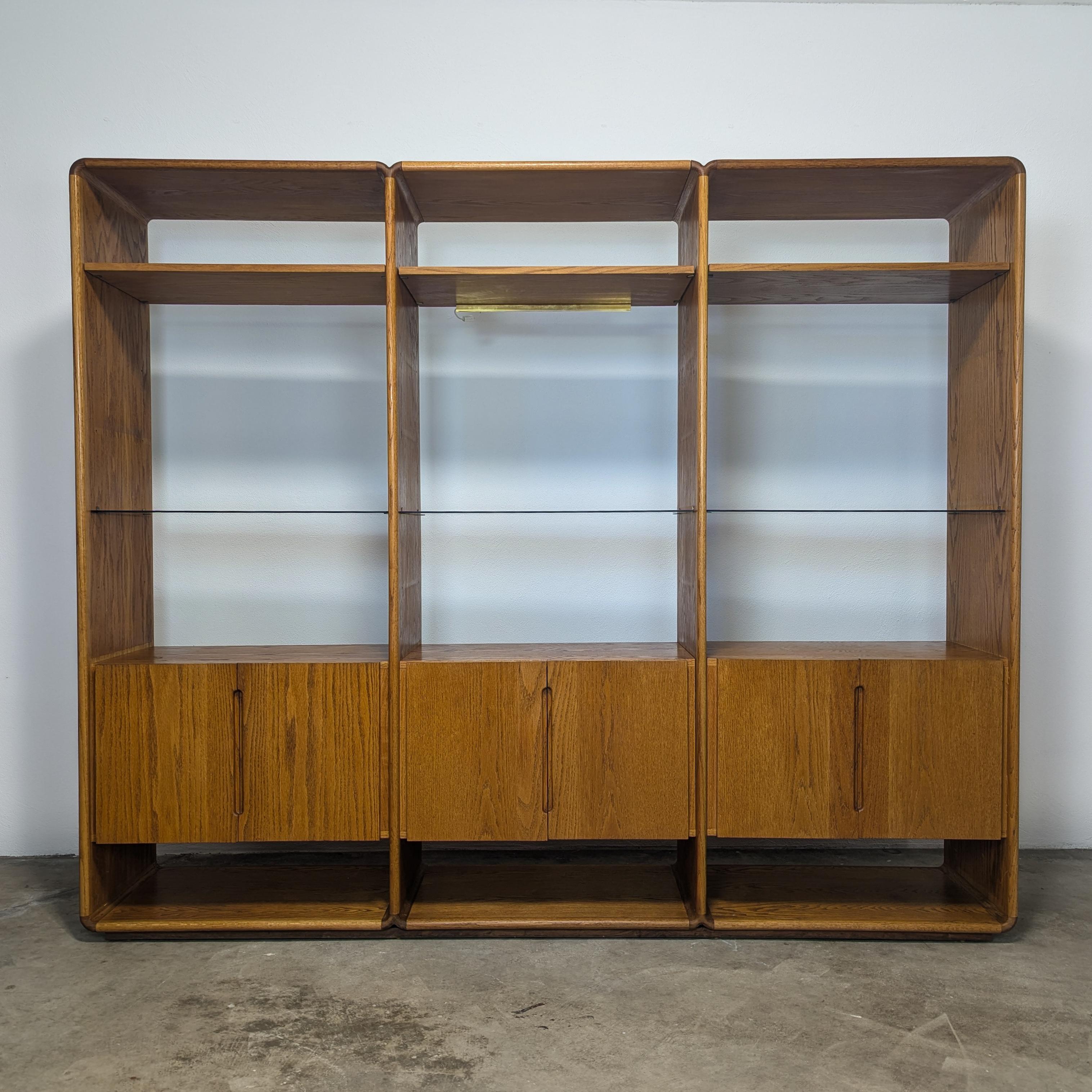 Elevate your space with this stunning handcrafted vintage wall cabinet, designed by the renowned Lou Hodges for California Design Group in 1979. This exceptional piece embodies the essence of mid-century modern design, featuring three sleek smoked