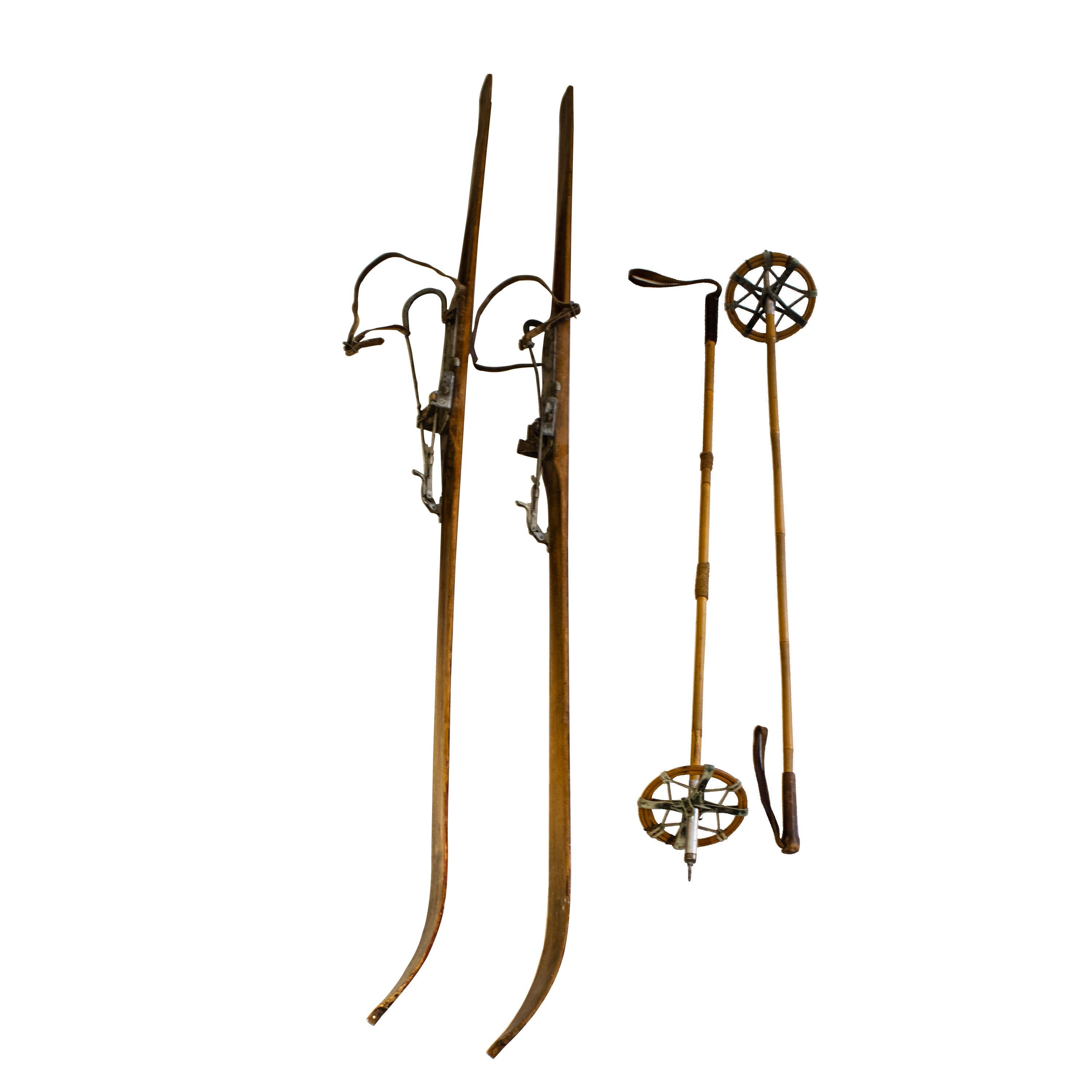 Ensemble de ski suisse fait à la main avec bâtons de ski. Les skis ont conservé les sangles d'orteils en cuir d'origine et les pièces métalliques de fixation d'origine qui sont un peu rouillées. Il présente des caractéristiques uniques telles qu'un