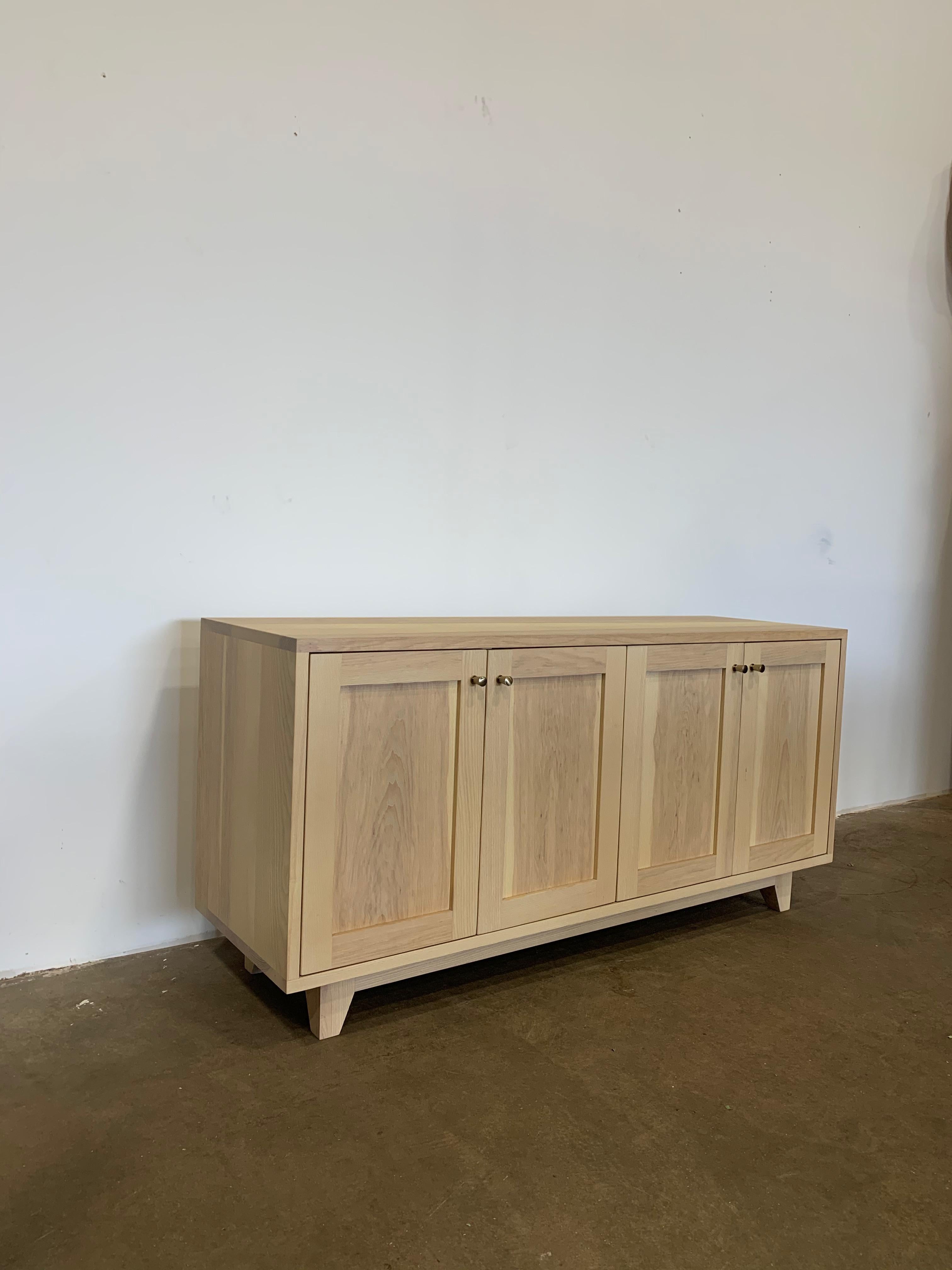 Solid ash console cabinet with white washed finish. 4 solid recessed panel doors with 2 adjustable shelves. Really happy with the base on this cabinet as well. This was a sample piece and it has minimal wear and is in excellent condition. 

Size: