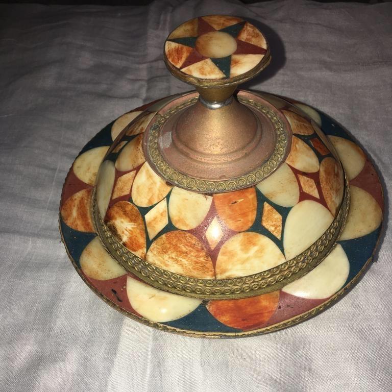 This lovely decorative tagine dish is made from brass, with inlaid repurposed camel or sheep bone. The bone is dyed with a natural henna. A decorative brass border encircles the lid and base of the lid handle, with a small silver mélange