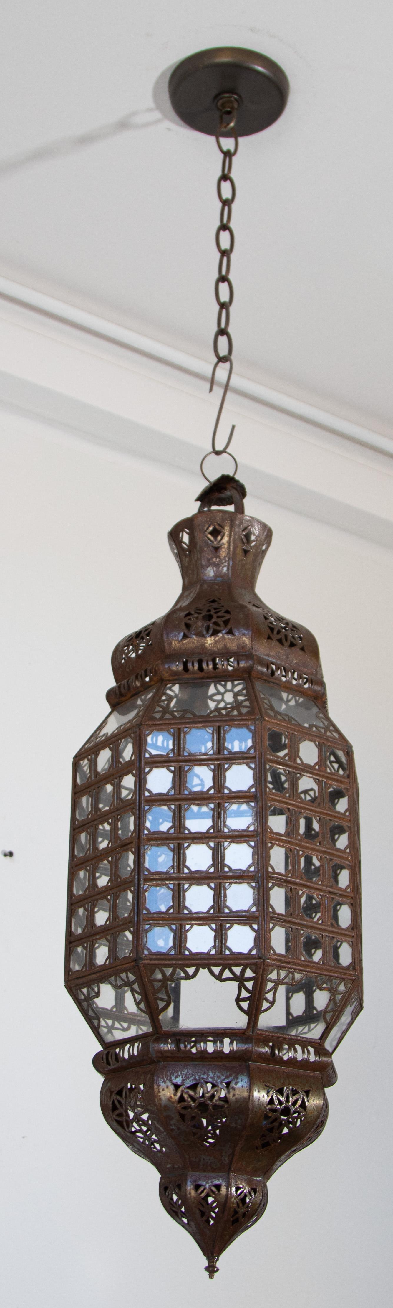 Lanterne marocaine élégante fabriquée à la main avec un verre transparent et un design de mosaïque mauresque en filigrane métallique.
Finition bronze antique.
Pendentif en verre de style mauresque composé d'une douzaine de petits verres taillés et