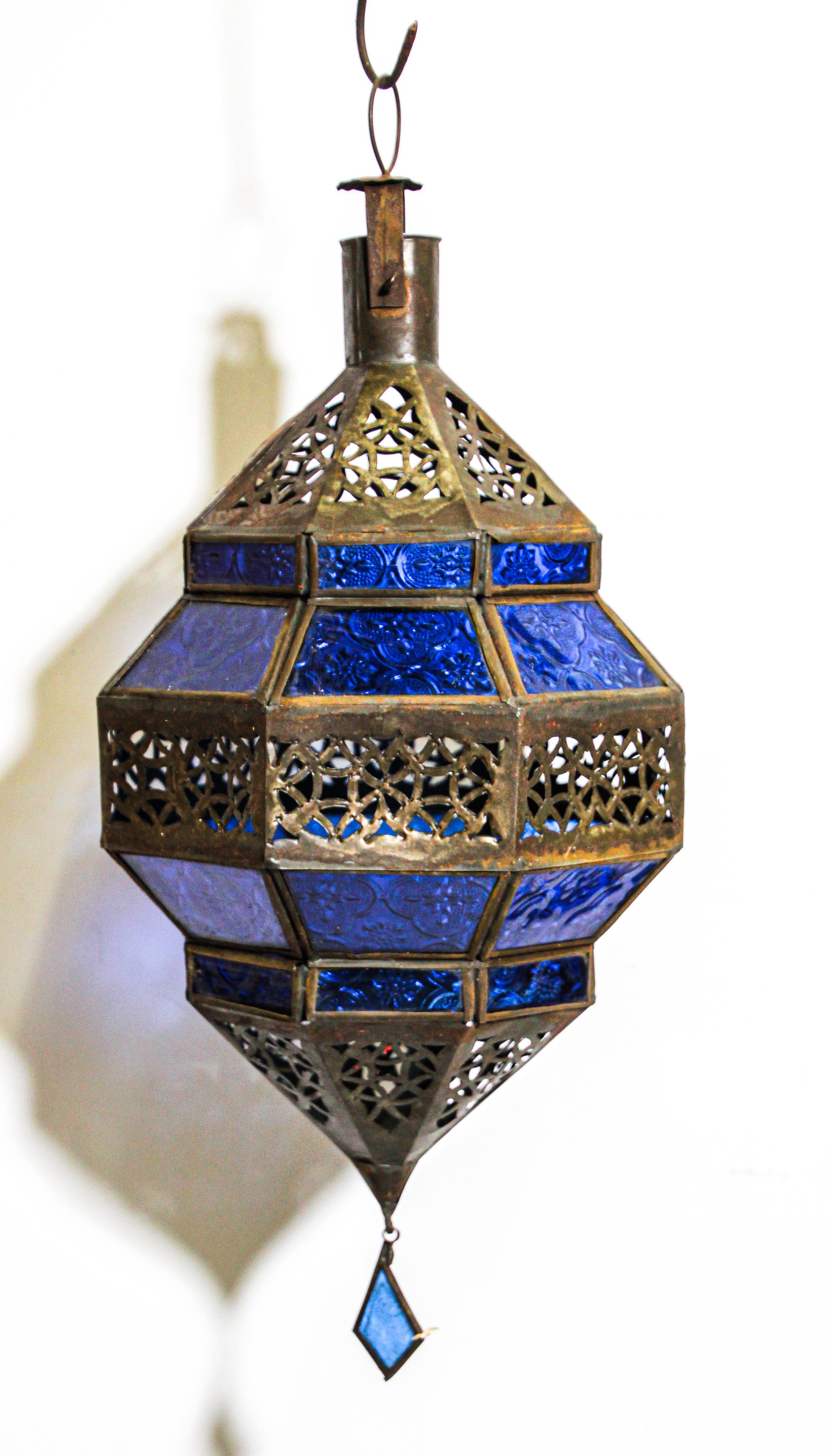 Moroccan metal and blue glass lantern in diamond shape. Moroccan lantern in octagonal shape with rust color metal finish and blue glass. The top and bottom with open metal work Moorish design. This Moroccan lantern when lit will cast light on the