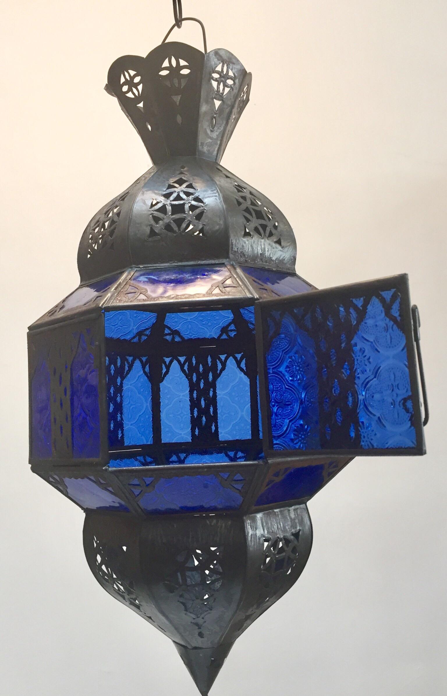 Moroccan metal and blue glass lantern. Moroccan lantern in octagonal shape with rust color metal finish and blue glass. The top and bottom metal hand-cut in openwork Moorish design. Moroccan lighting will cast light on the walls with pretty patterns