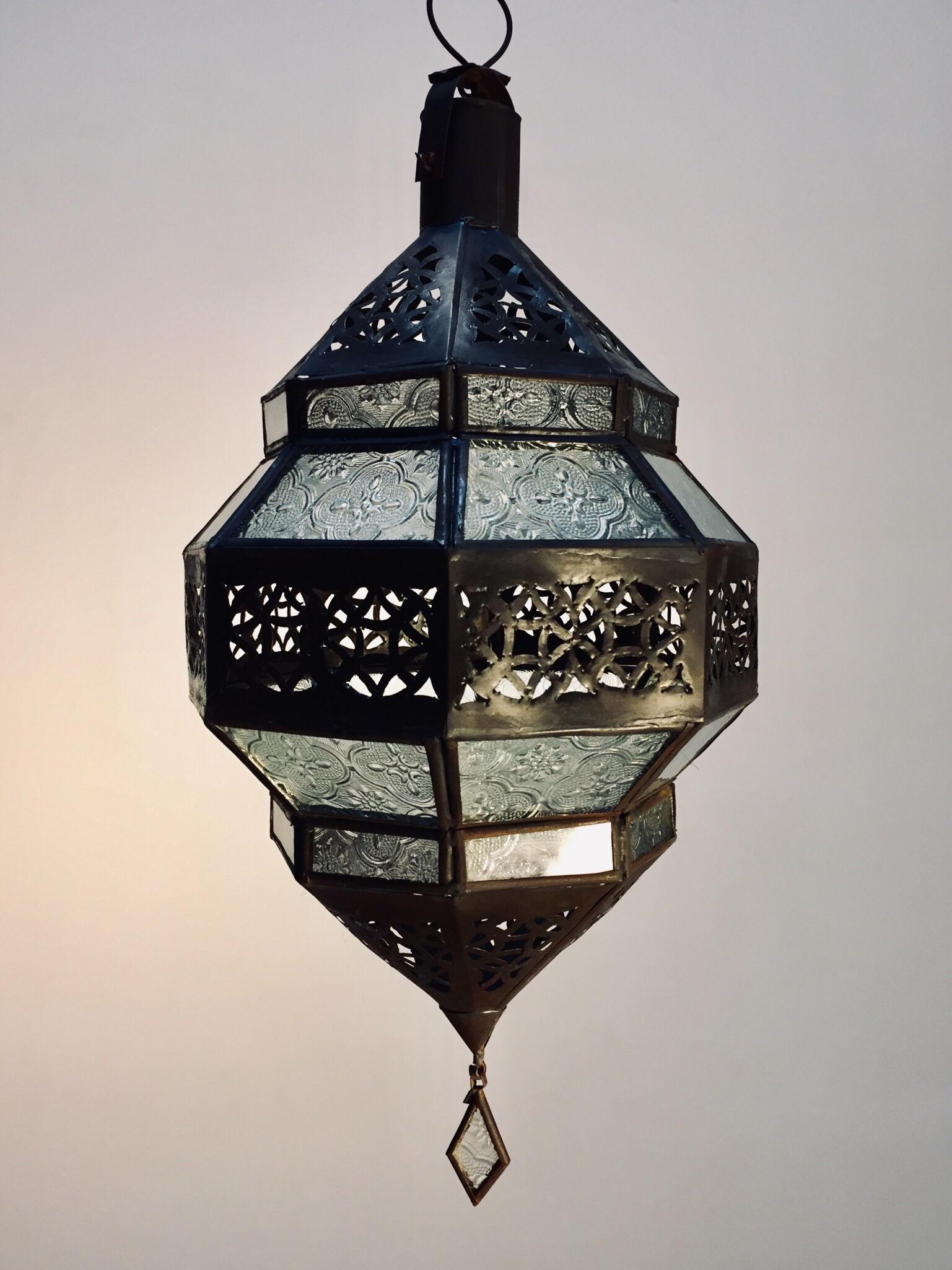 Moroccan metal and clear frosted glass lantern.
Moroccan lantern in octagonal shape with rust color metal finish and clear glass.
The top and bottom metal hand-cut in openwork Moorish design.
This Moroccan lantern  when lit will cast light on the