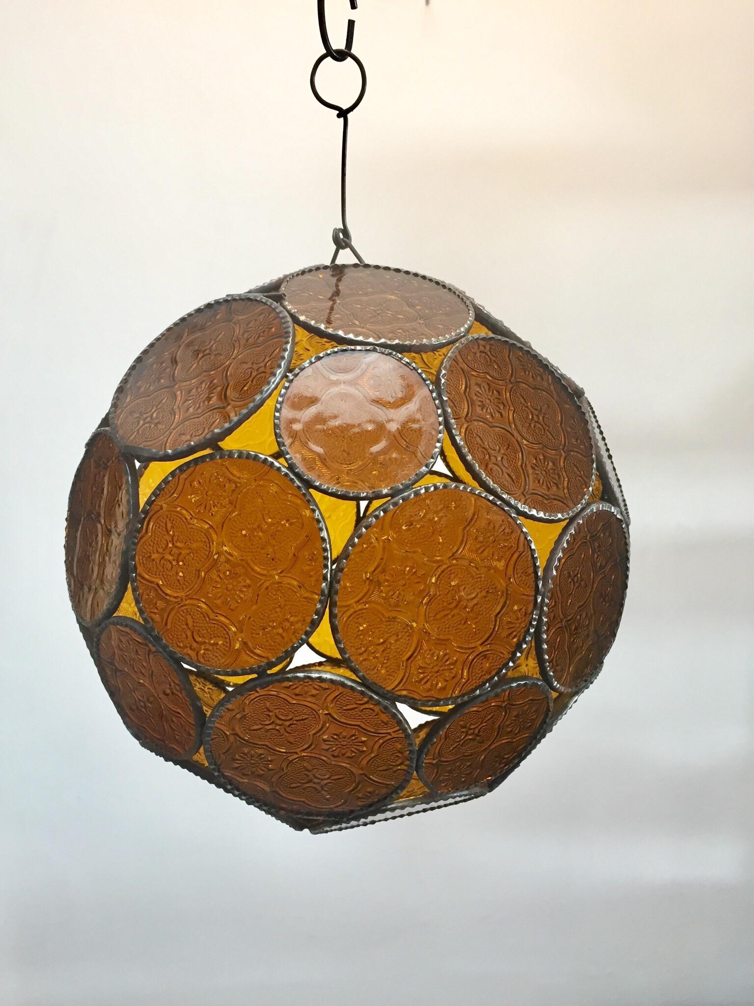 Handcrafted Moroccan amber glass lantern or Moorish pendant.
Amber molded glass with Moorish design circles put together in an orb style lamp.
Handmade in Marrakech, metal rust color finish, colorful multifaceted orb glass pendant.
Could be
