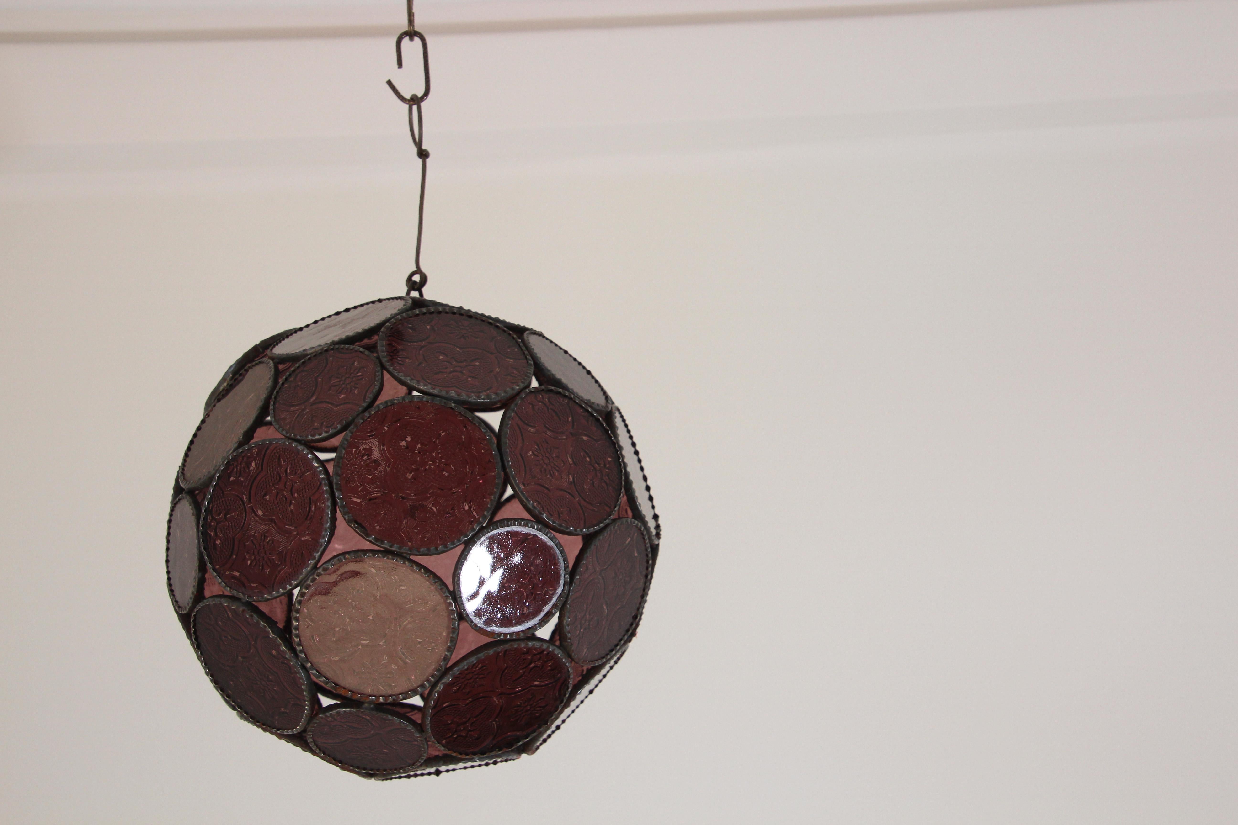 Handcrafted Moroccan lavender glass lantern or Moorish pendant.
Amber molded glass with Moorish design circles put together in an orb style lamp.
Handmade in Marrakech, metal rust color finish, colorful multifaceted orb glass pendant.
Could be